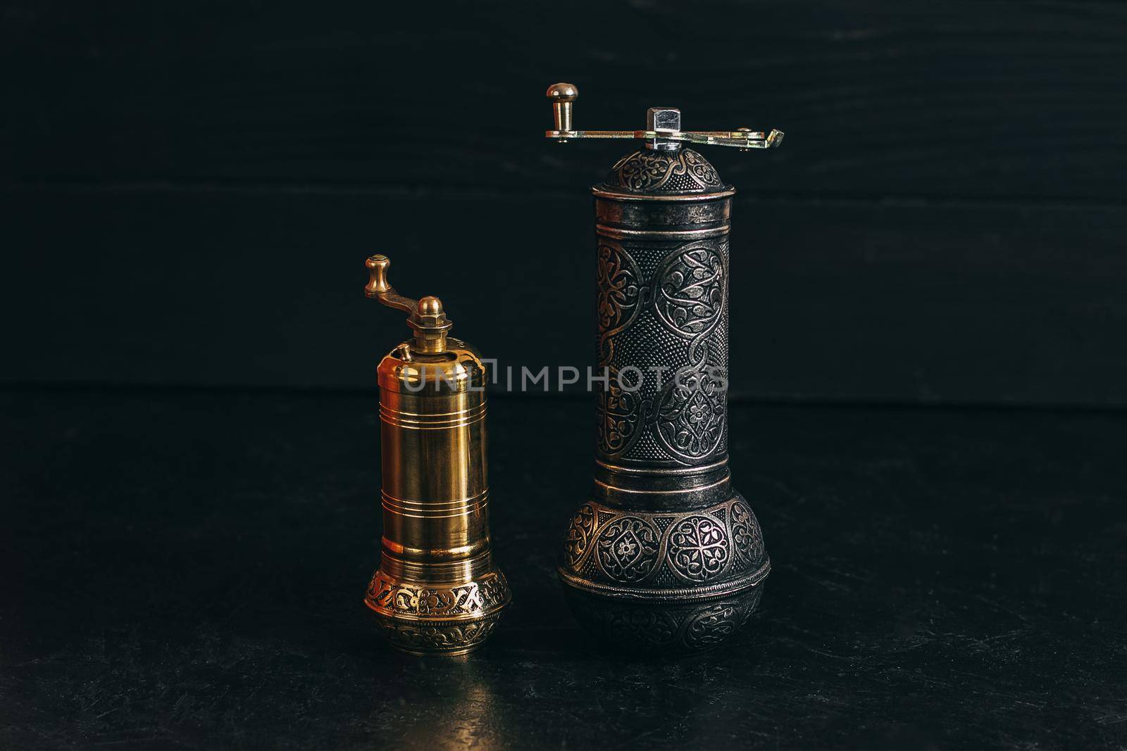 Pepper or coffee vintage metal grinder on a dark black background.