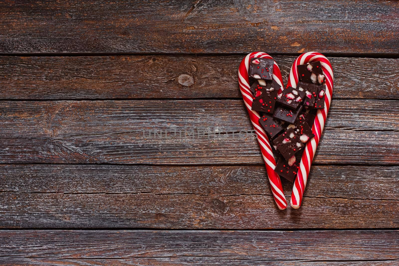 Red heart-shaped lollipop and chocolates of valentines day on wood texture background. Valentines day background.