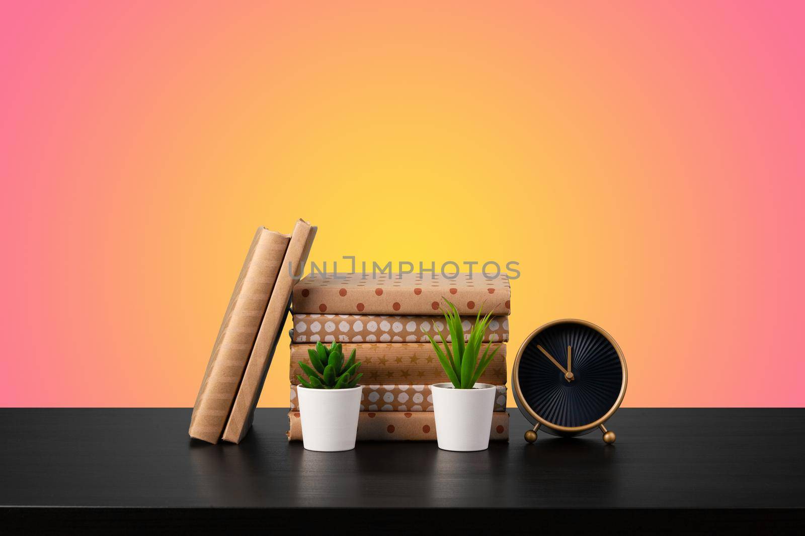 Education concept with stack of books on a table against colored background, front view