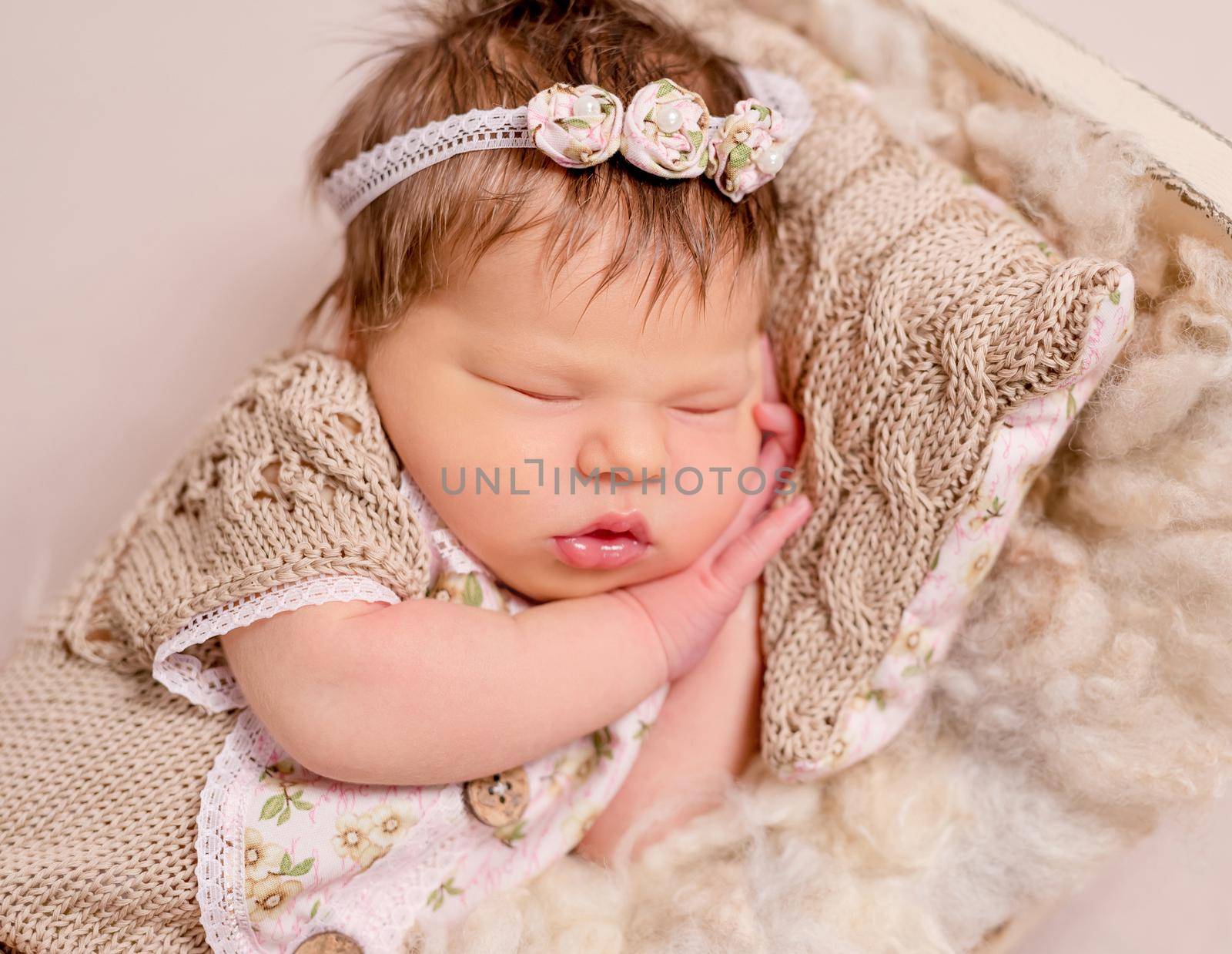 Cute little baby in knitted beanie and skirt sweetly sleeping on the light coverlet