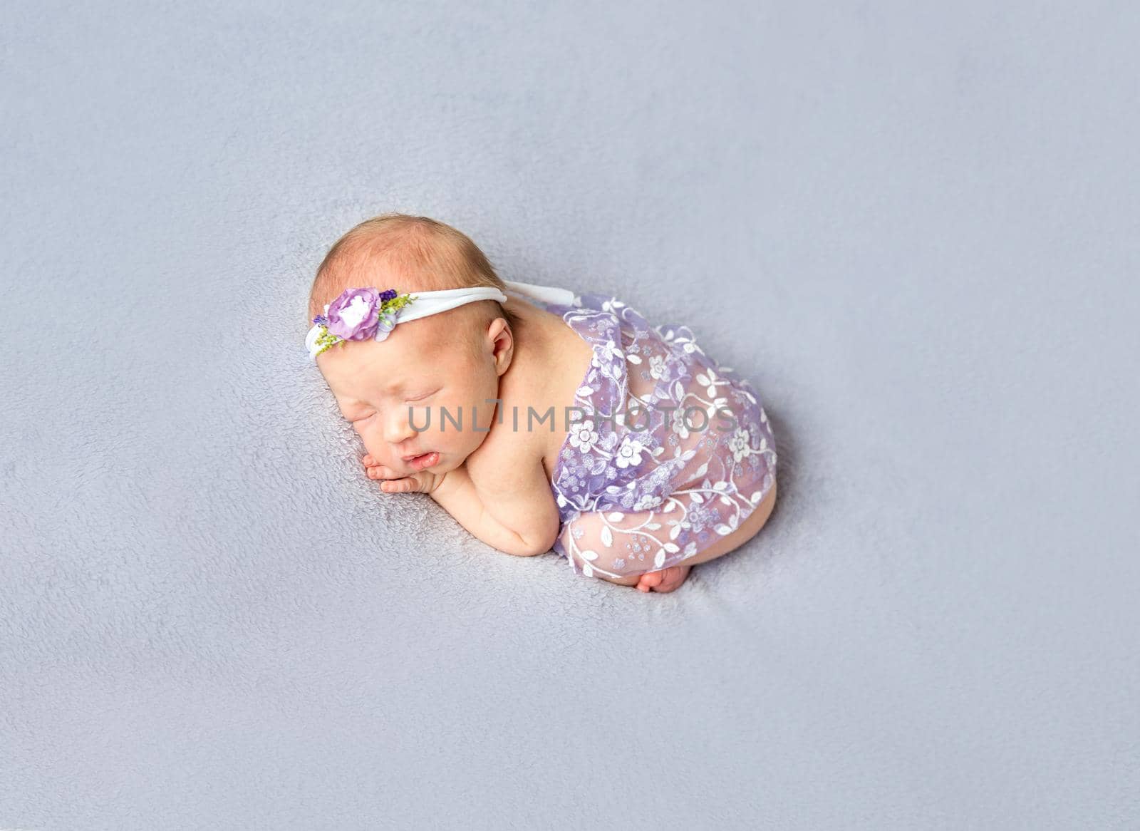 Sweet infant girl sleeping in a funny pose, covered with a light flowery scarf