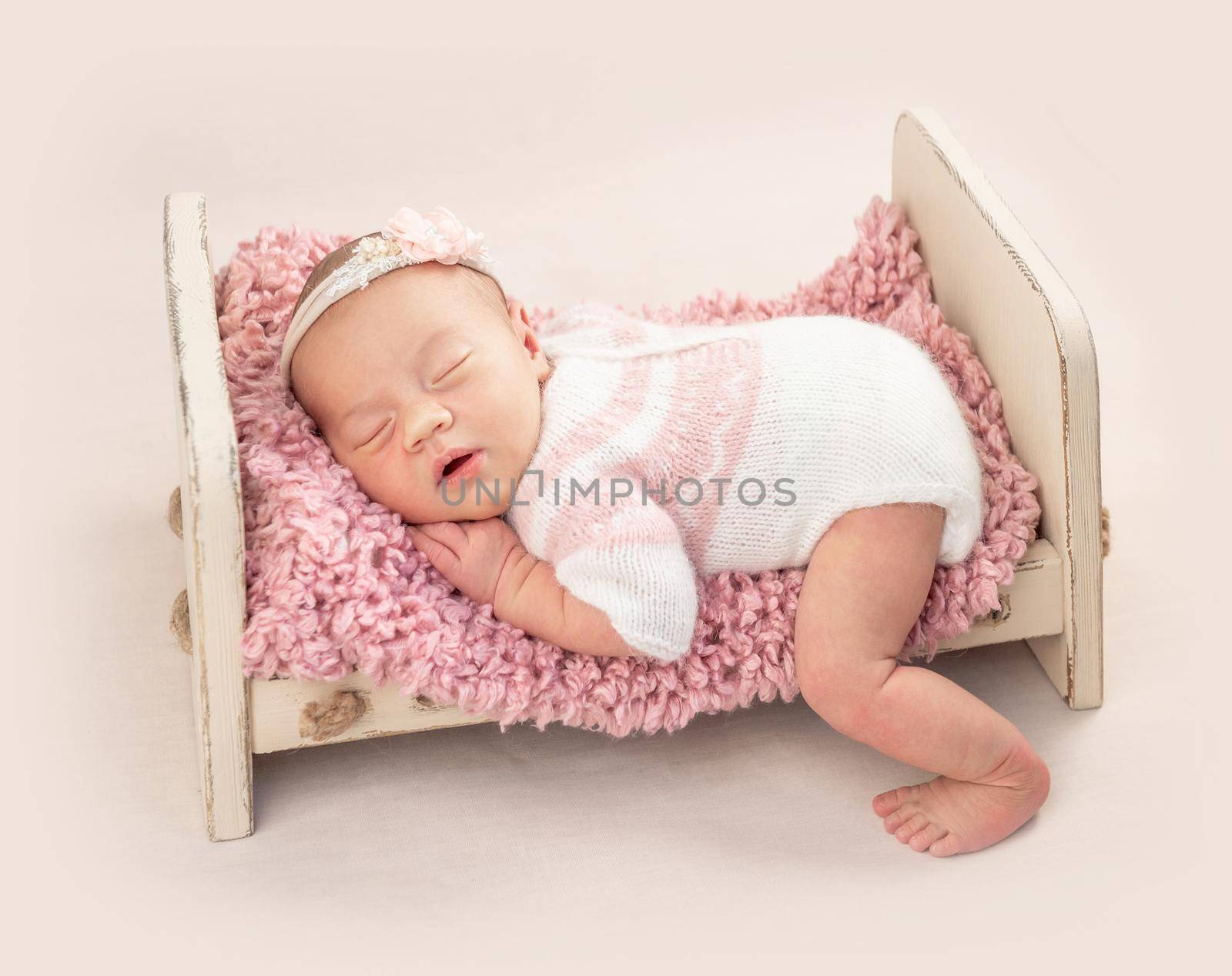 Little cutie infant in neatly knitted bodysuit on baby bed, isolated on white background