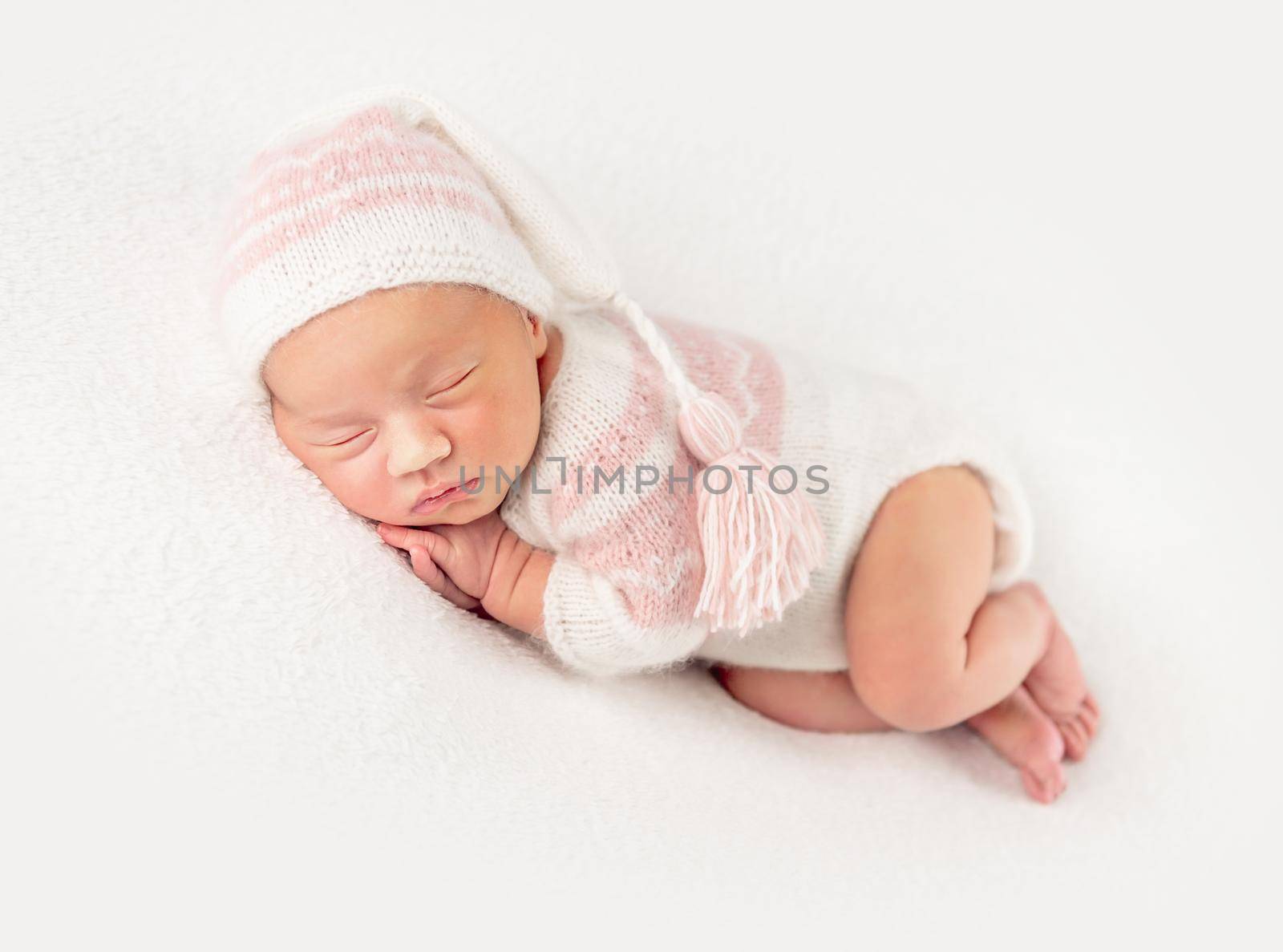 Pretty baby girl in creamy knitted suit and hat, isolated on white background