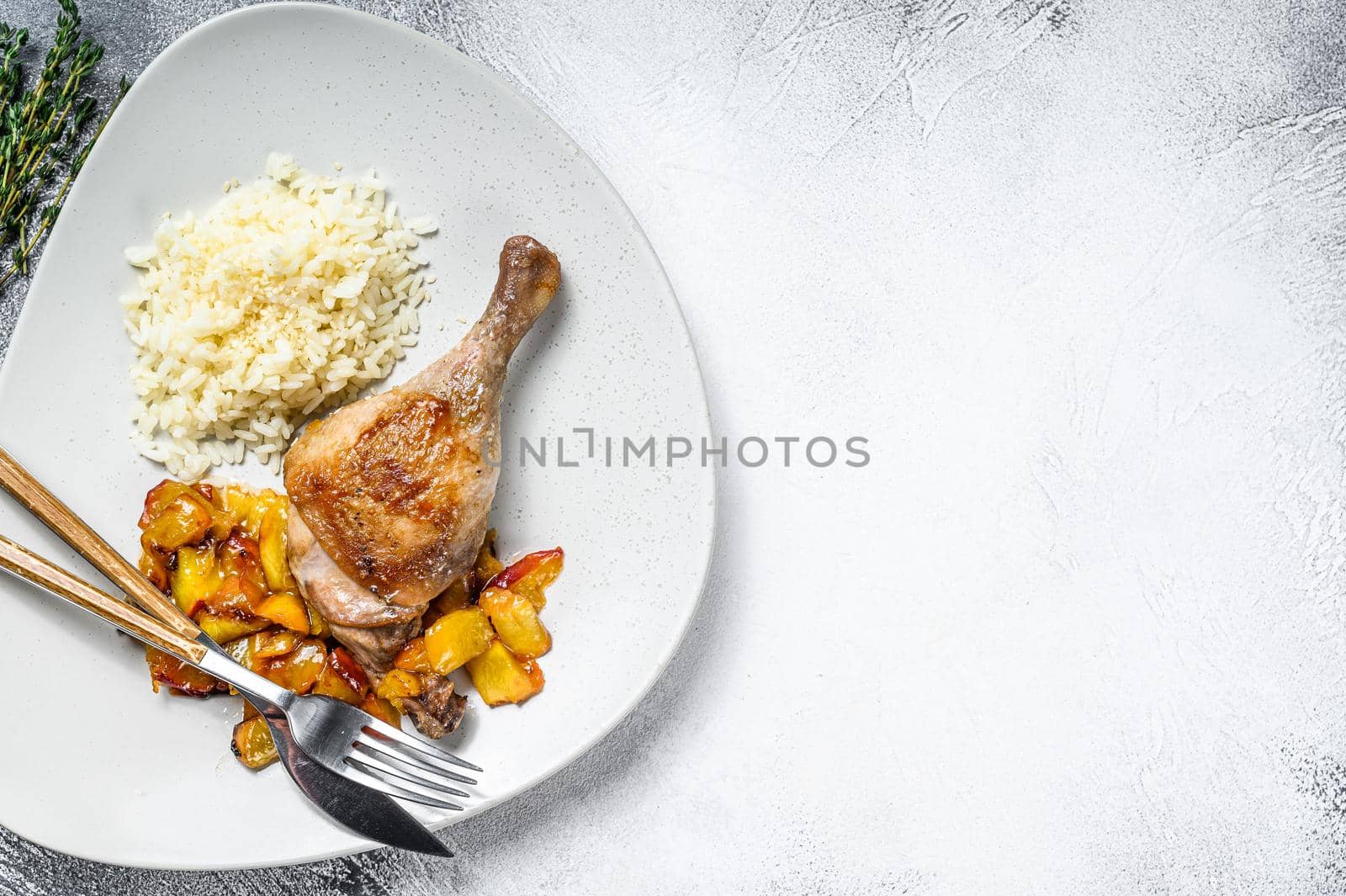 Baked duck legs with oranges, peach and spices. White background. Top view. Copy space.