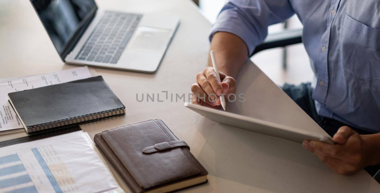 Businessman working on digital tablet marking few imports points with a stylus. Male entrepreneur checking finance report on his tablet computer by nateemee