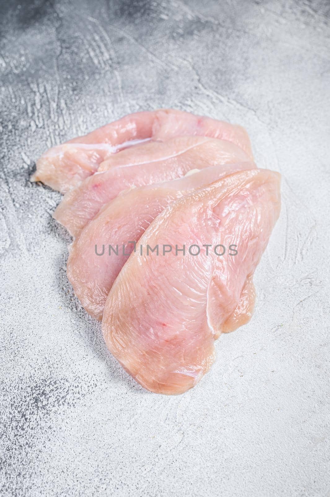 Raw sliced chicken breast fillet steaks. White background. Top view. by Composter