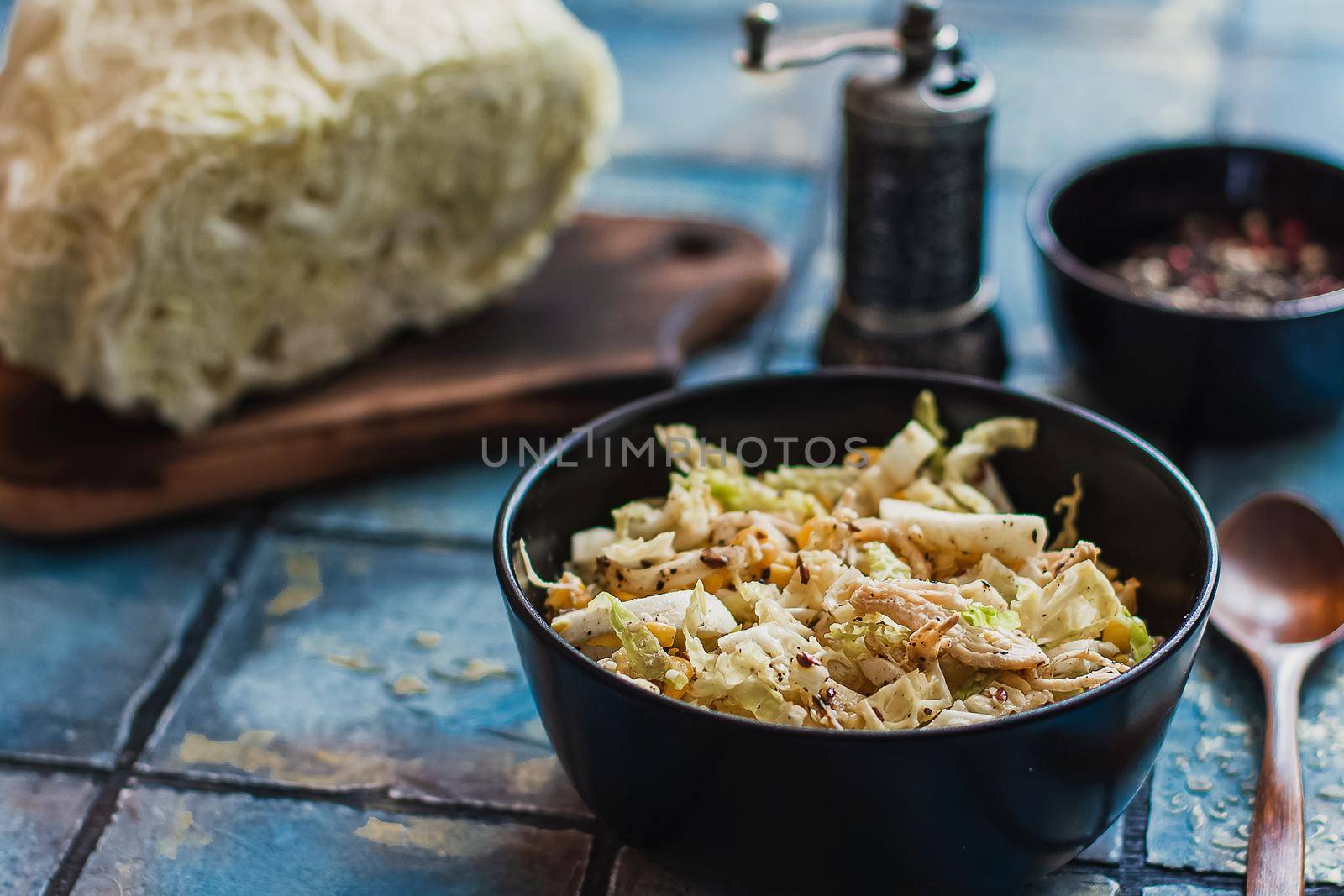 Salad with cabbage, eggs, corns and meat on the plate on rustic tiled table.