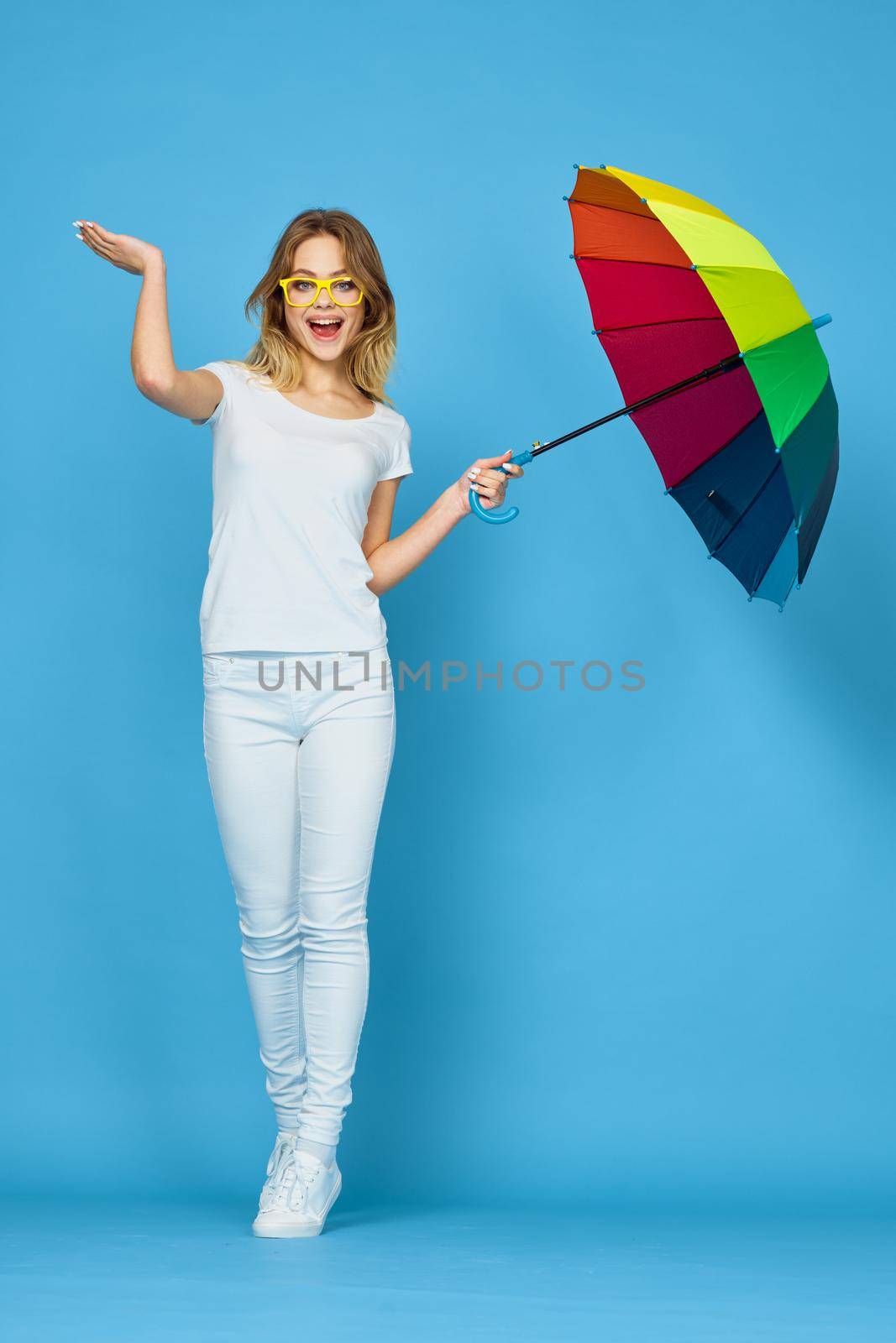 fashionable woman with umbrella rainbow colors posing blue background by Vichizh