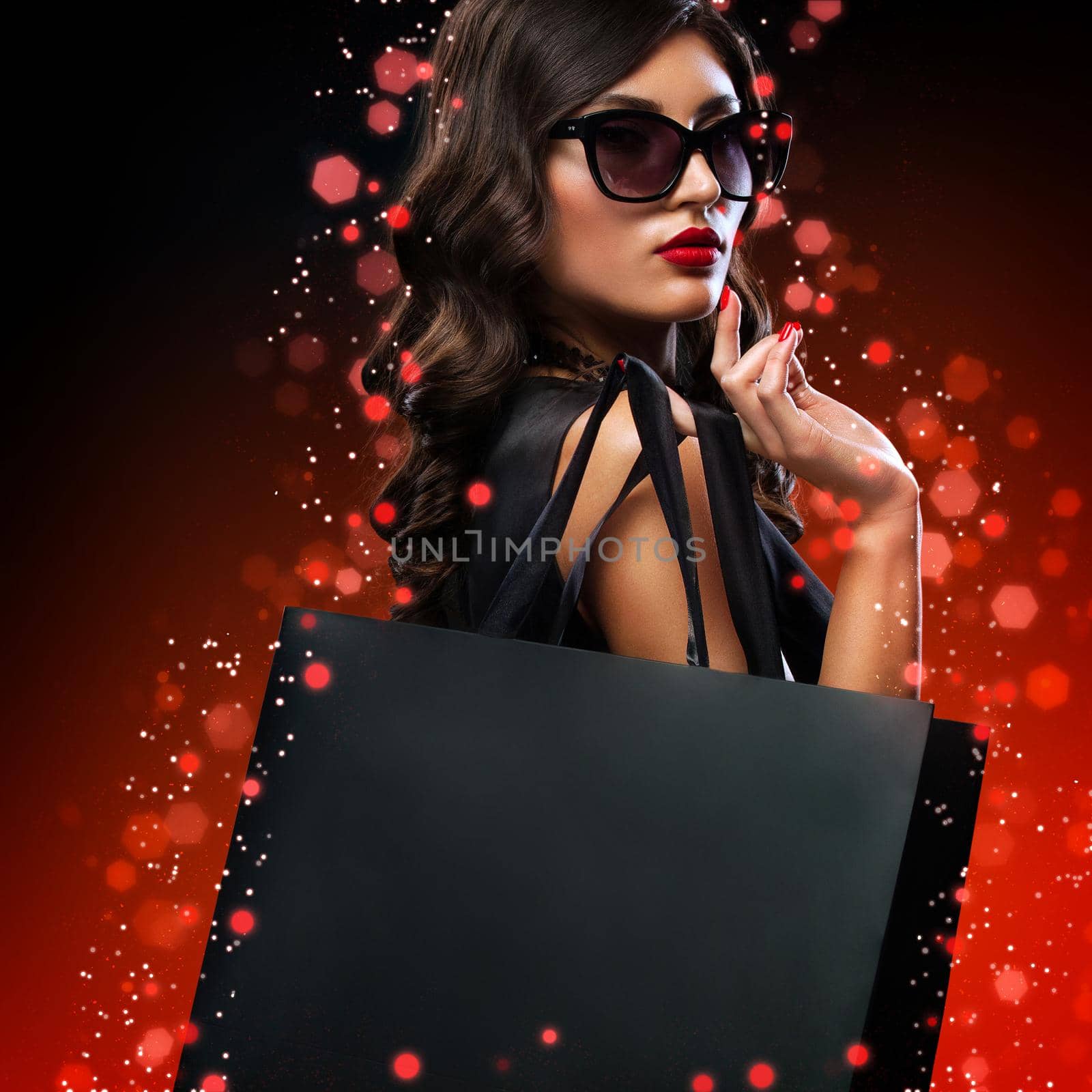 Beautiful young woman make shopping in black friday holiday. Girl with black bag on dark background.