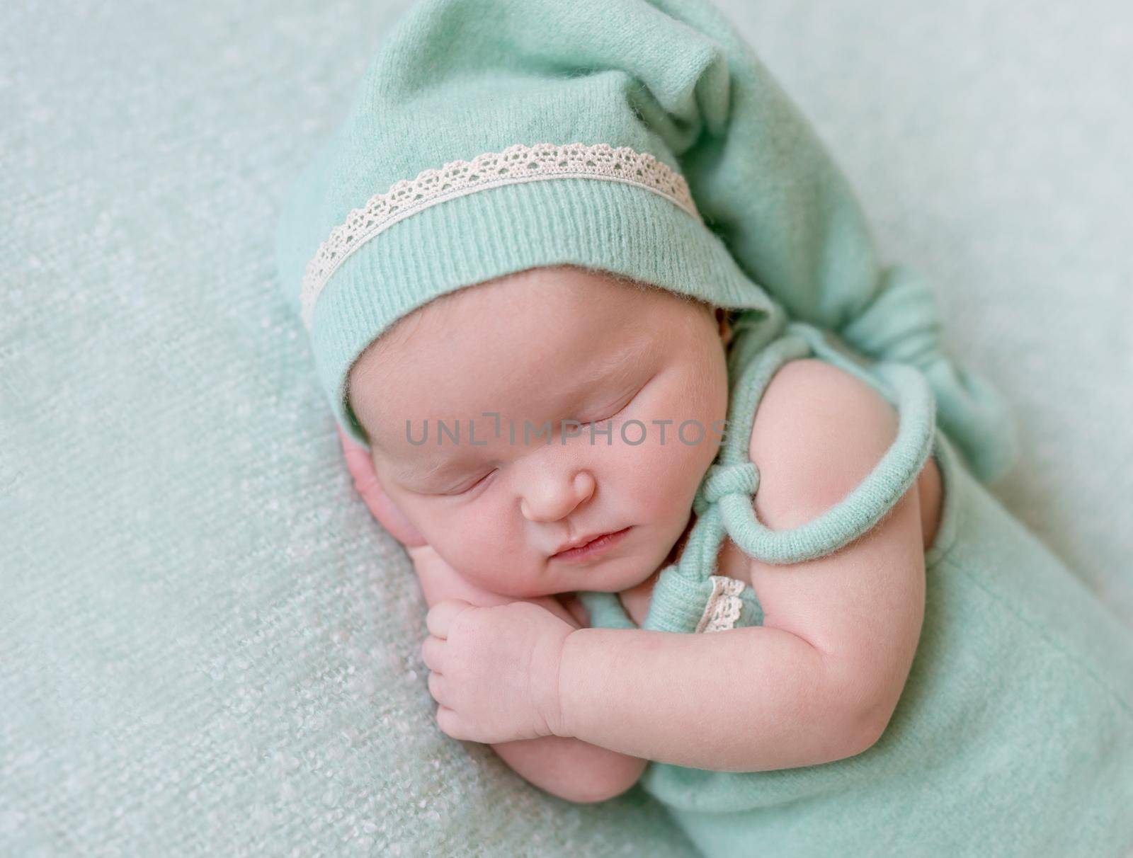 Cute girl sleeping on her side in green hat, wearing green small outfit, closeup