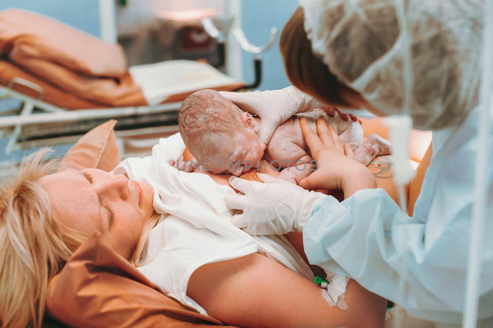 Close-up of a newborn feeding on the mother's sternum in the maternity ward of a hospital, immediately after birth