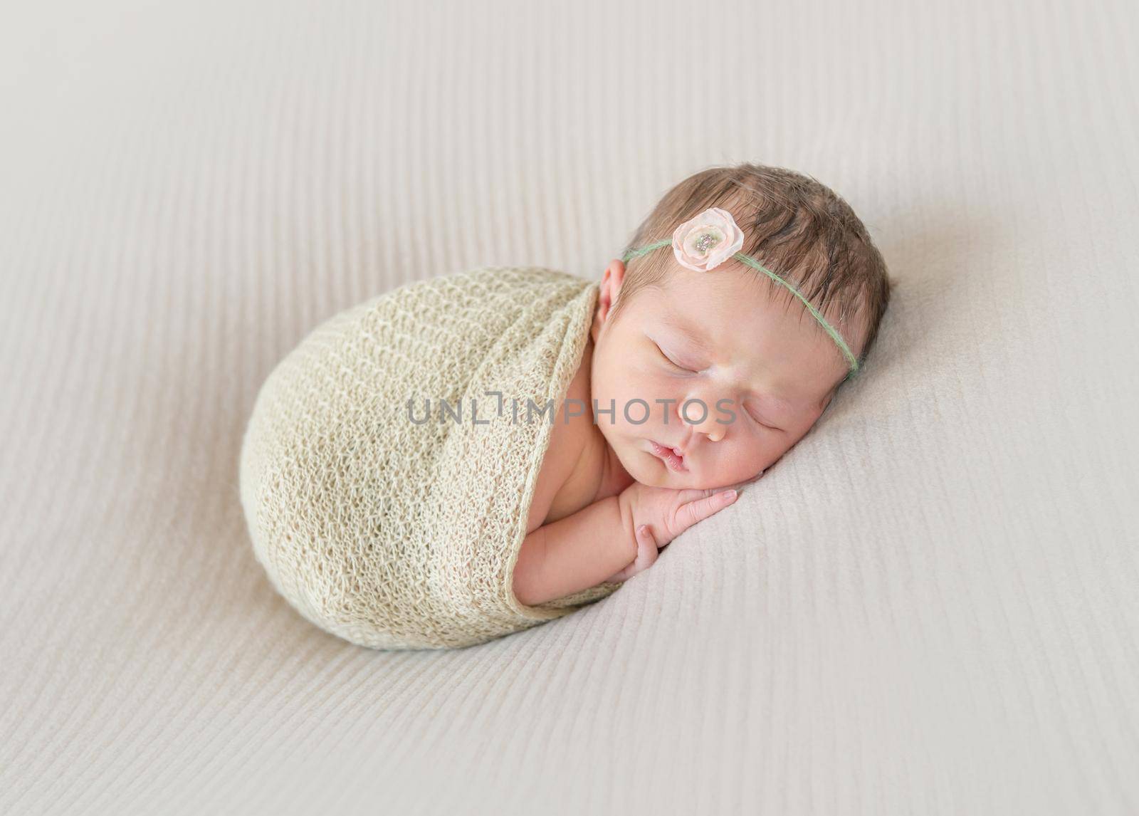 Adorable kid napping wrapped with a scarf, arm hanging out of it, sleeping tight