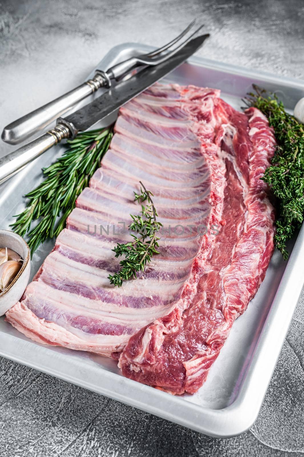Raw uncooked rack of mutton lamb ribs in baking dish. White background. Top view.