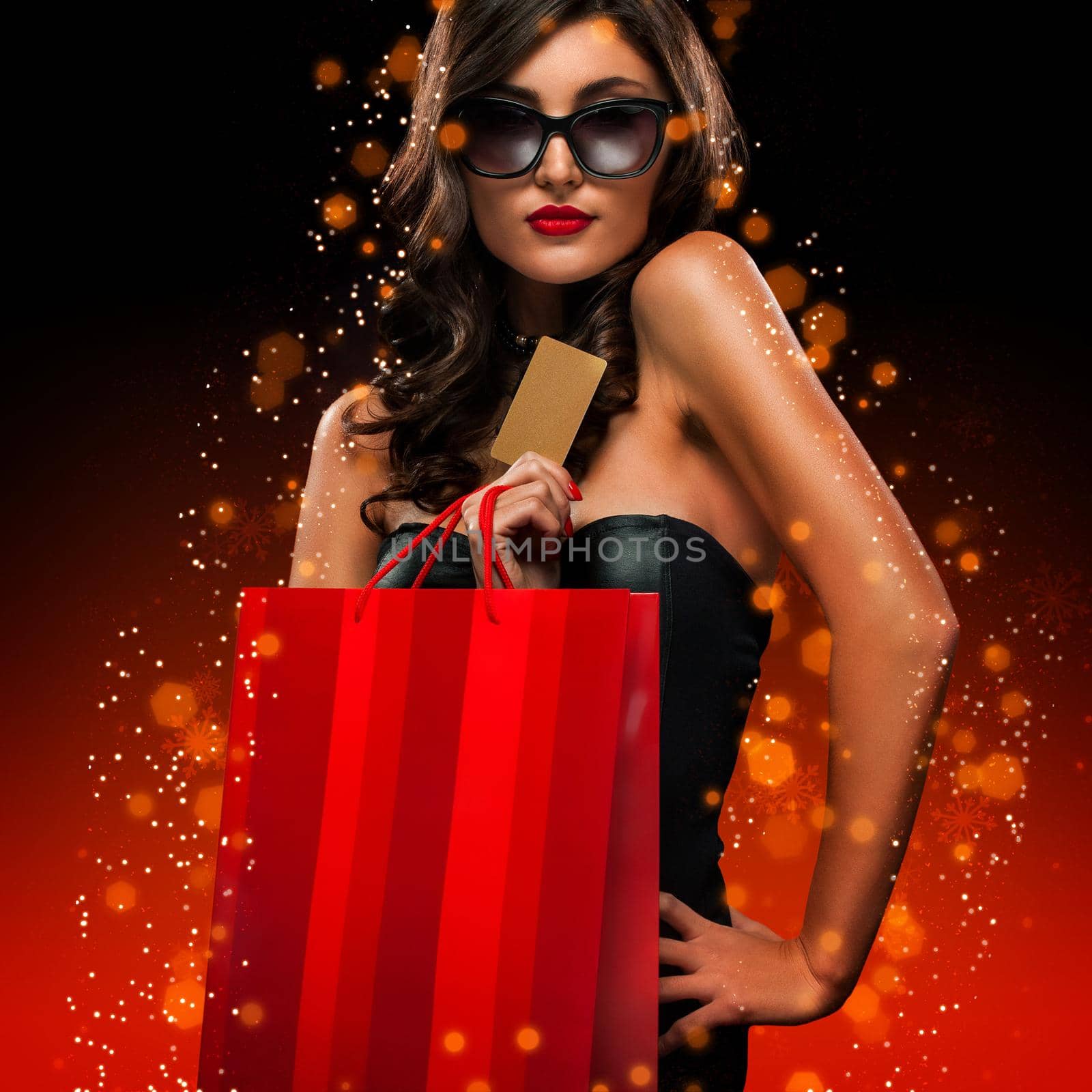 Christmas and Black friday sale concept. Shopping woman holding red bag isolated on dark background in holiday by MikeOrlov