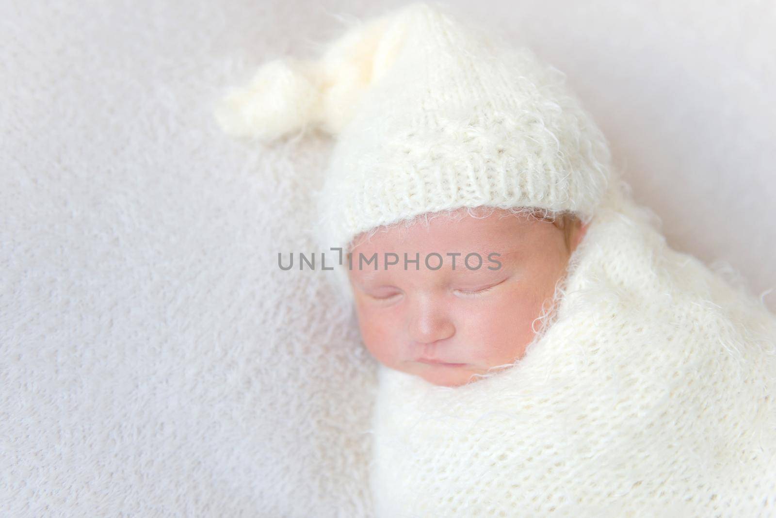 infant wearing a warm white hat sleeping, closeup by tan4ikk1