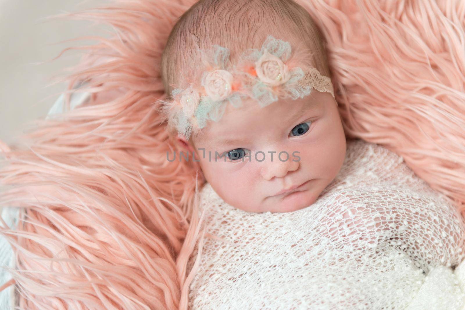 Cute baby girl watching the world, big curious eyes, wearing a lovely flowery hairband, topview