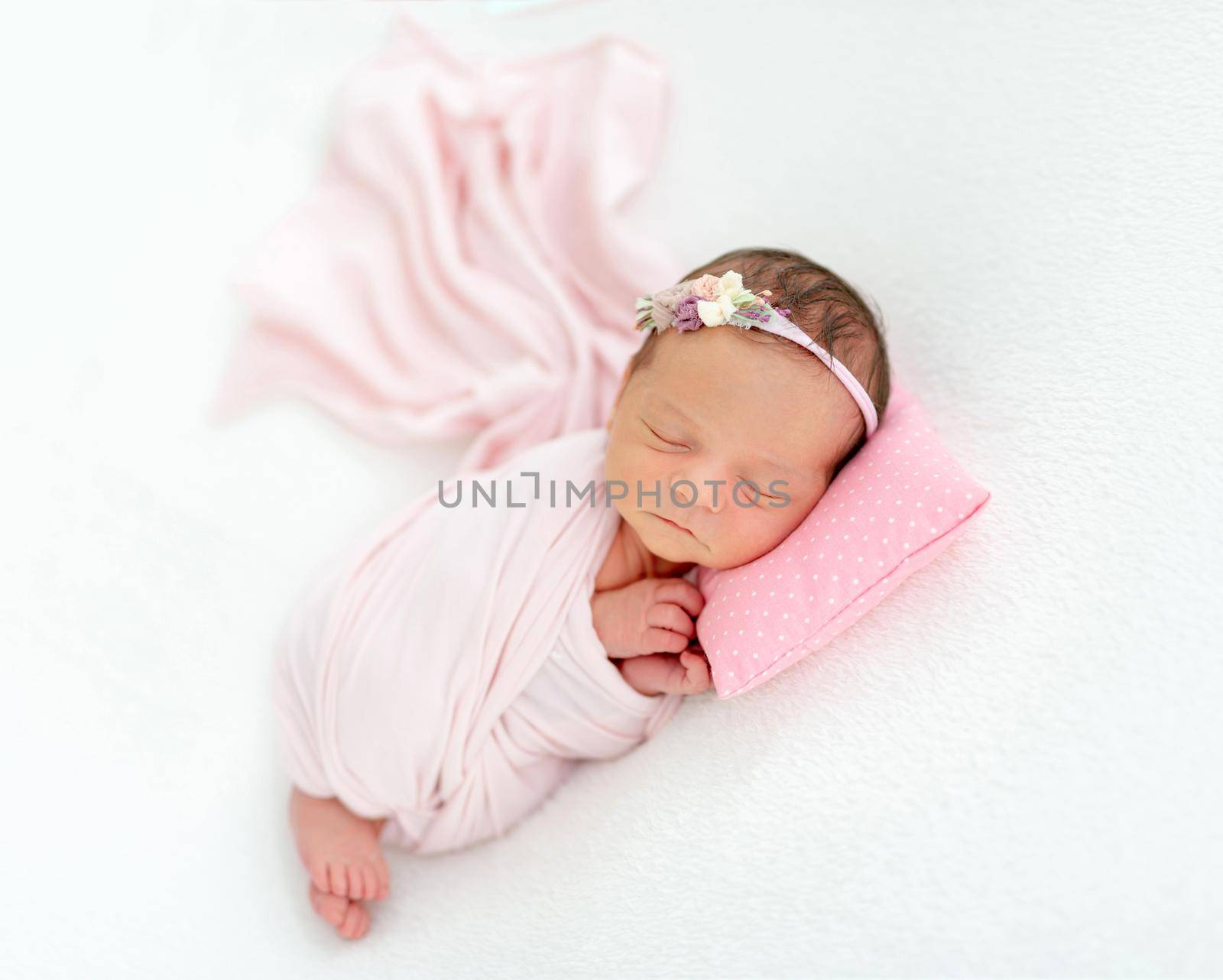 newborn baby girl sleeping sweetly on a little pillow