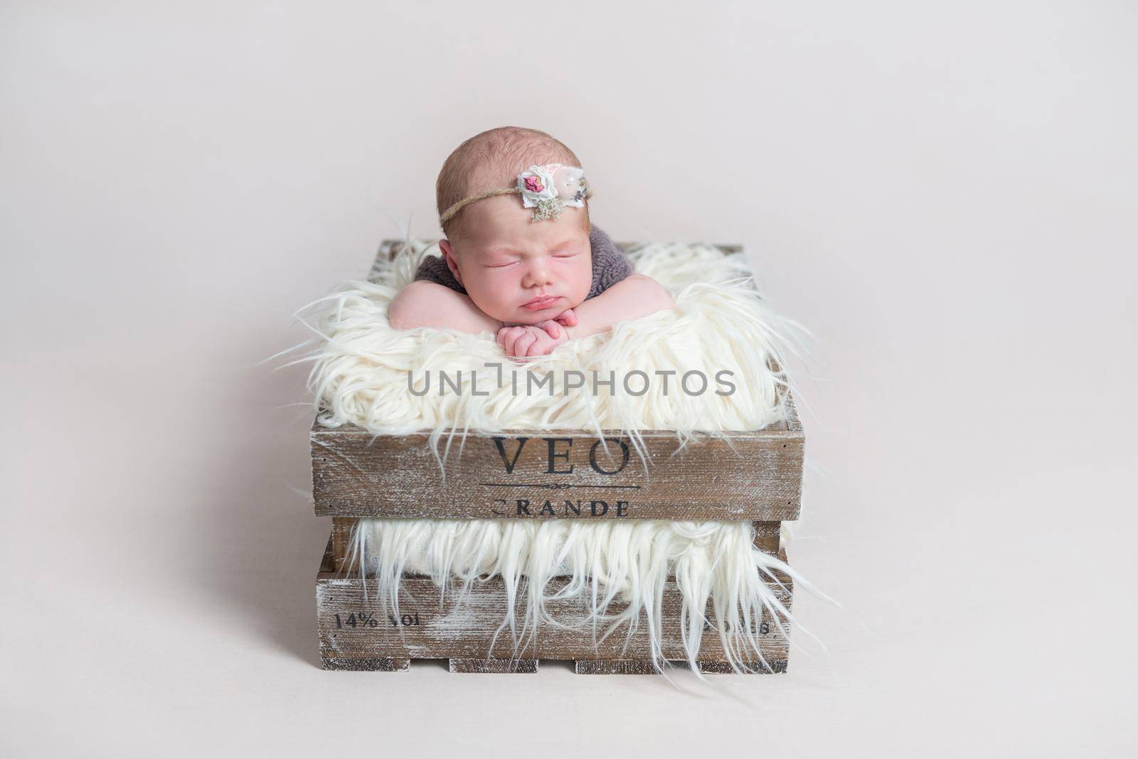 Sweet cute baby girl sleeping on her belly in rustic massive basket, on furry pillow