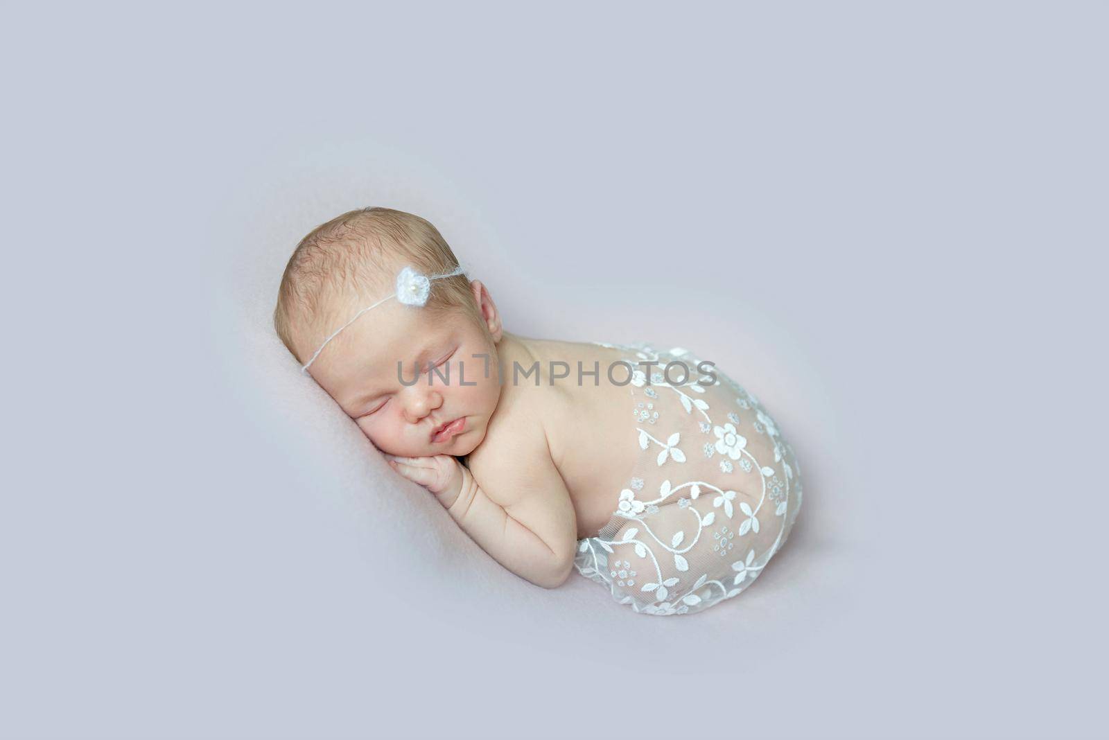 Sweet baby covered with laced scarf with tiny flowers sleeping tightly on belly, curled up