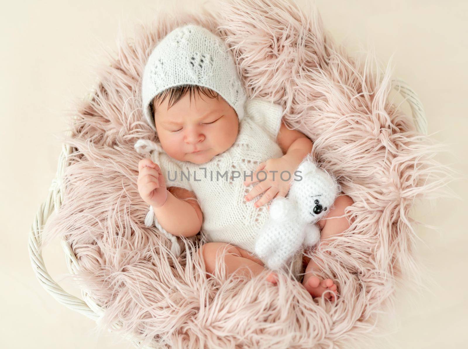 newborn baby girl sleeping sweetly in the basket with a small toy