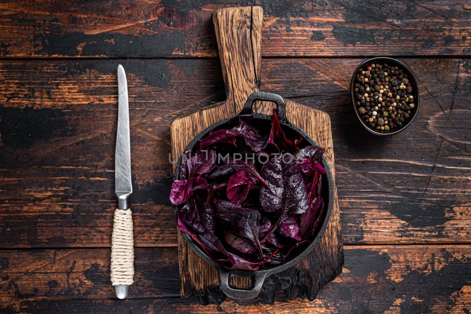 Swiss red chard or Mangold salad Leafs in a pan. Dark wooden background. Top view.