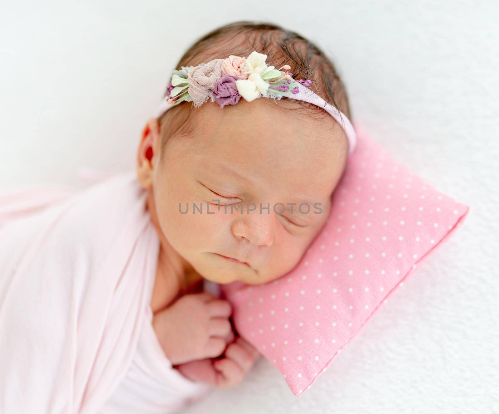 newborn baby girl sleeping sweetly on a little pillow