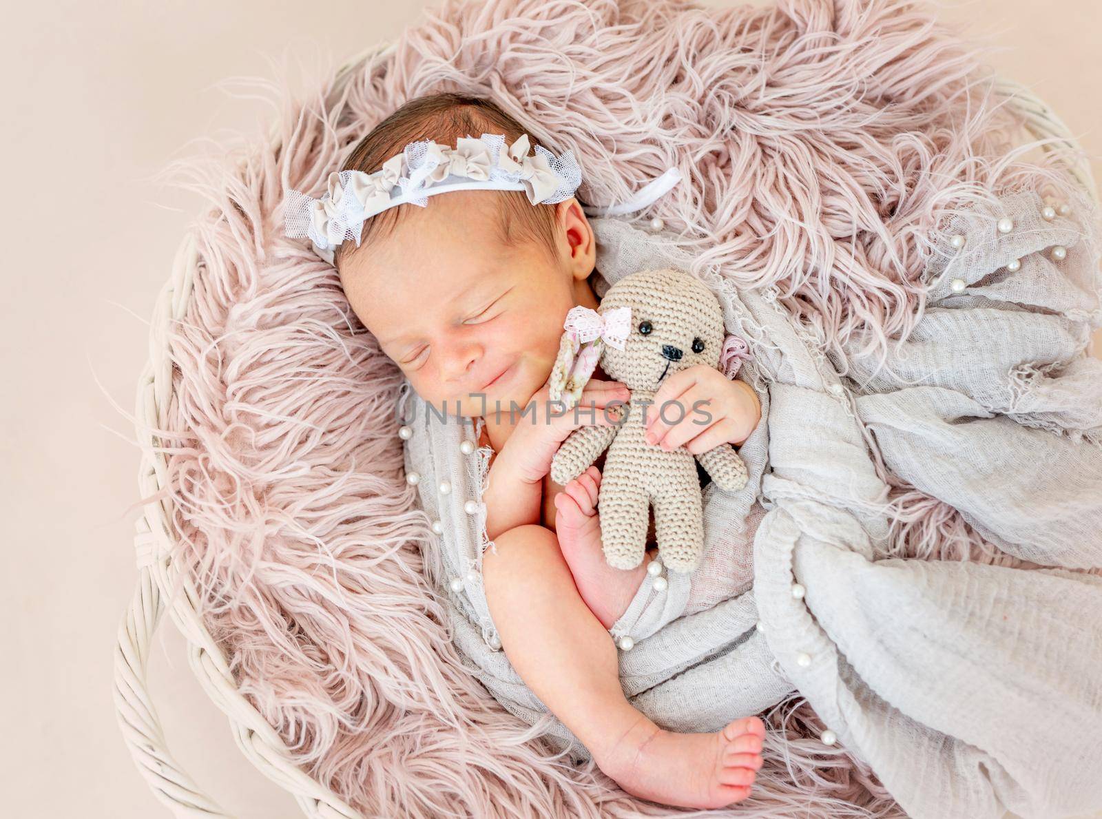 smiling newborn baby girl sleeping sweetly in the basket with a small toy