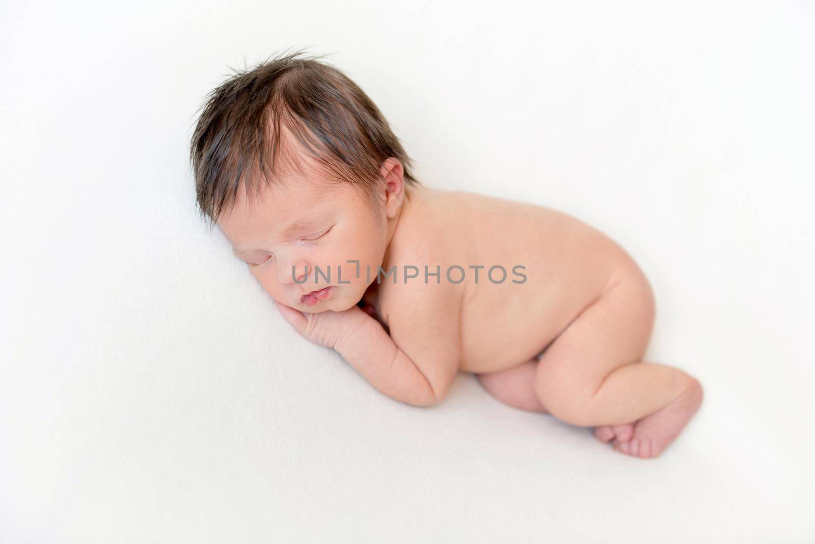 Dreamy newborn baby sleeping peacefully on the side on bed