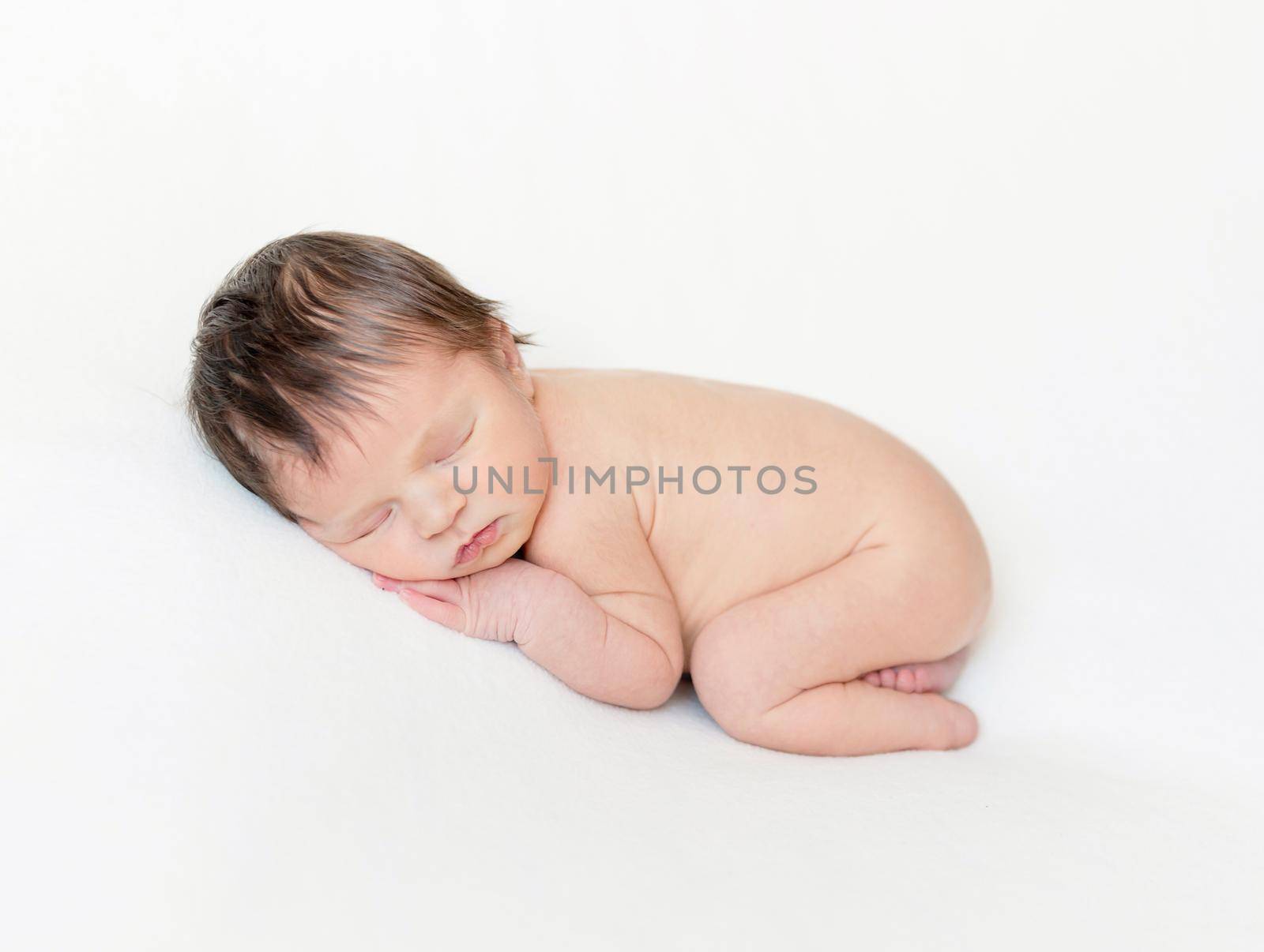 Dreamy newborn baby sleeping peacefully on the side on bed