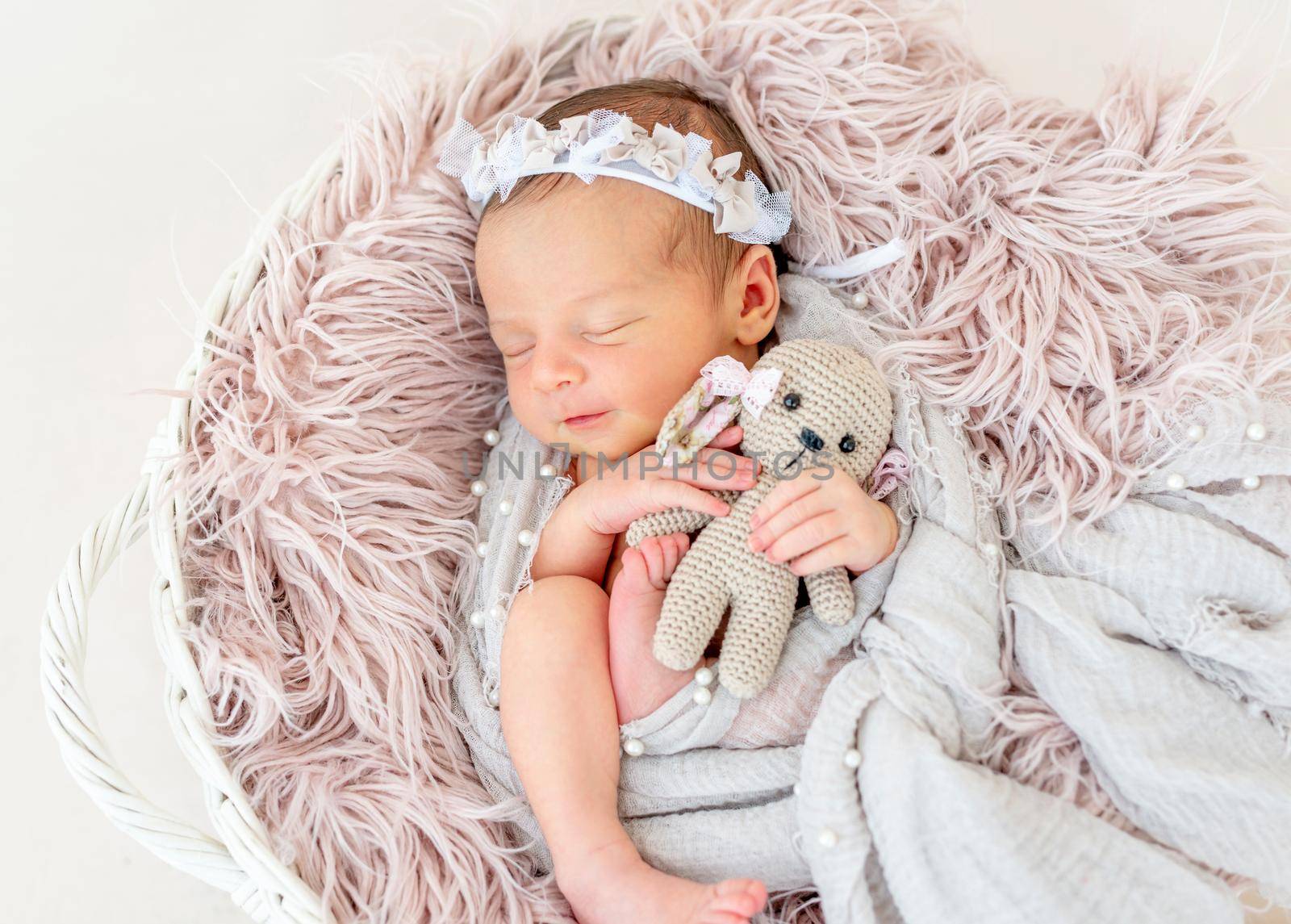 smiling newborn baby girl sleeping sweetly in the basket with a small toy