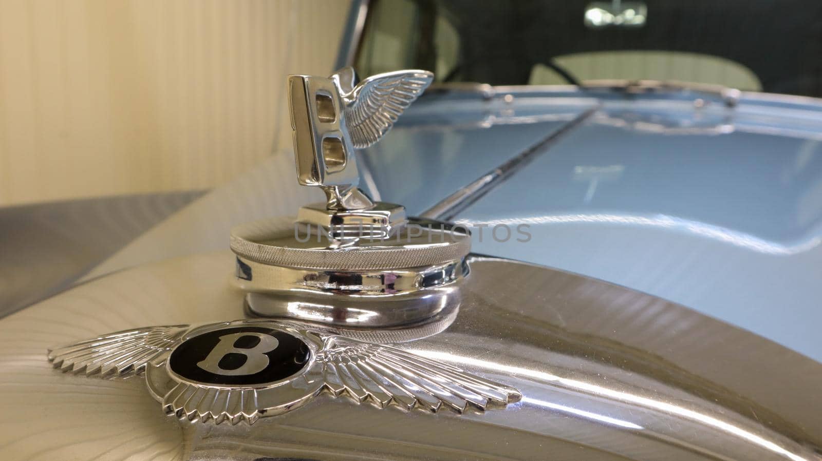 Close-up of a Bentley S1 badge on the hood of a 1950 Flying Spur luxury sedan. The logo is made in the form of a letter B with spread wings. Collectible model. Ukraine, Kiev - June 04, 2021