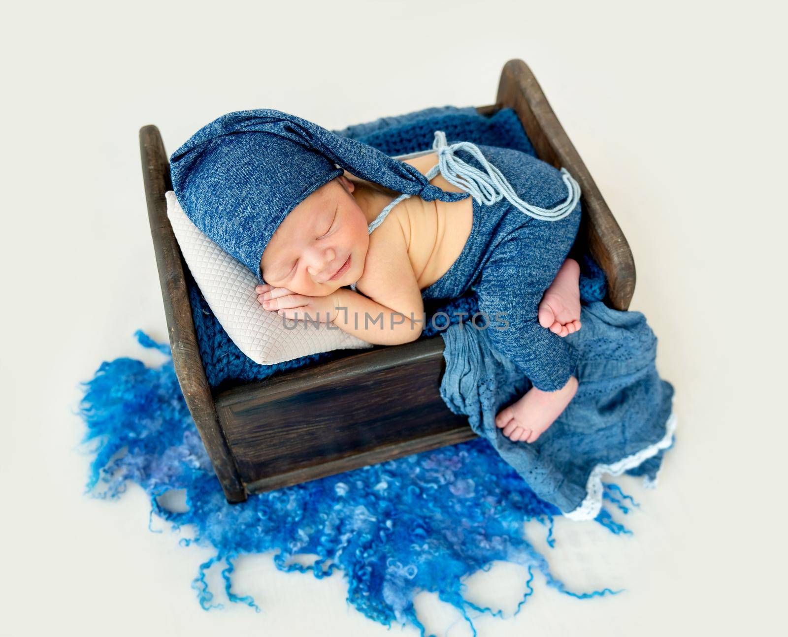 A little boy in a blue suit is sleeping sleeping in a little bed