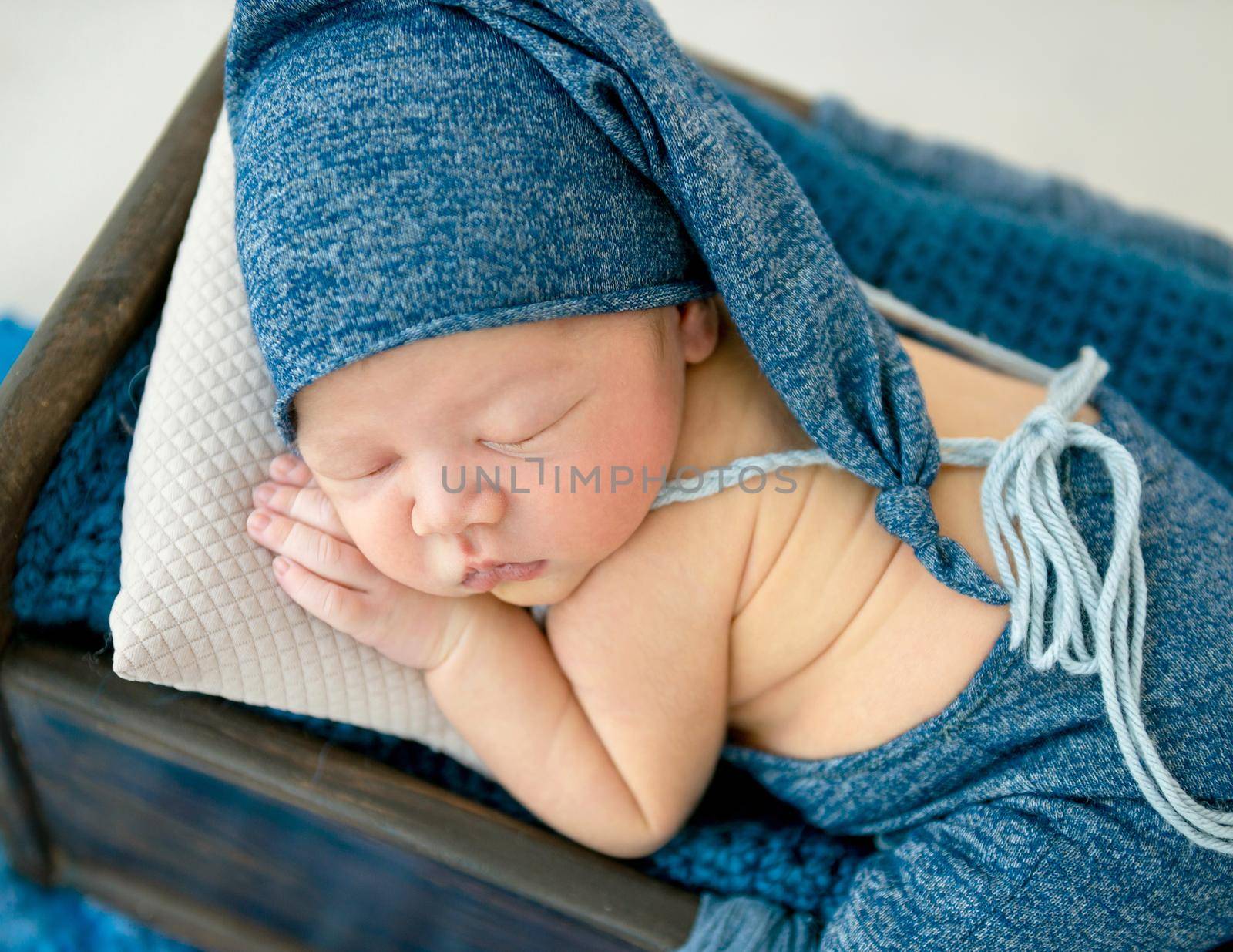 A little boy in a blue suit is sleeping sleeping in a little bed