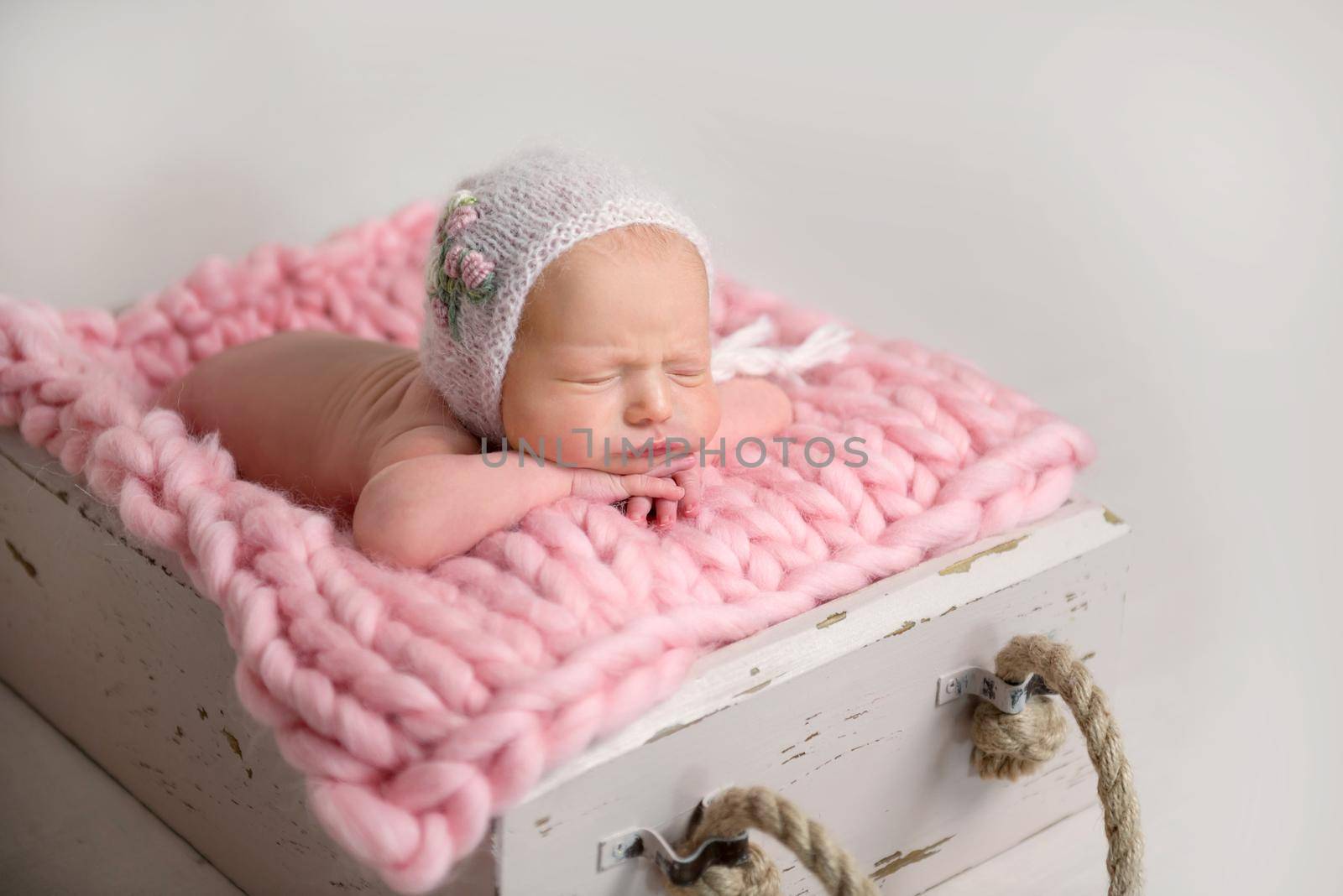 Sleeping newborn baby with chubby cheeks lying in box on rug by tan4ikk1