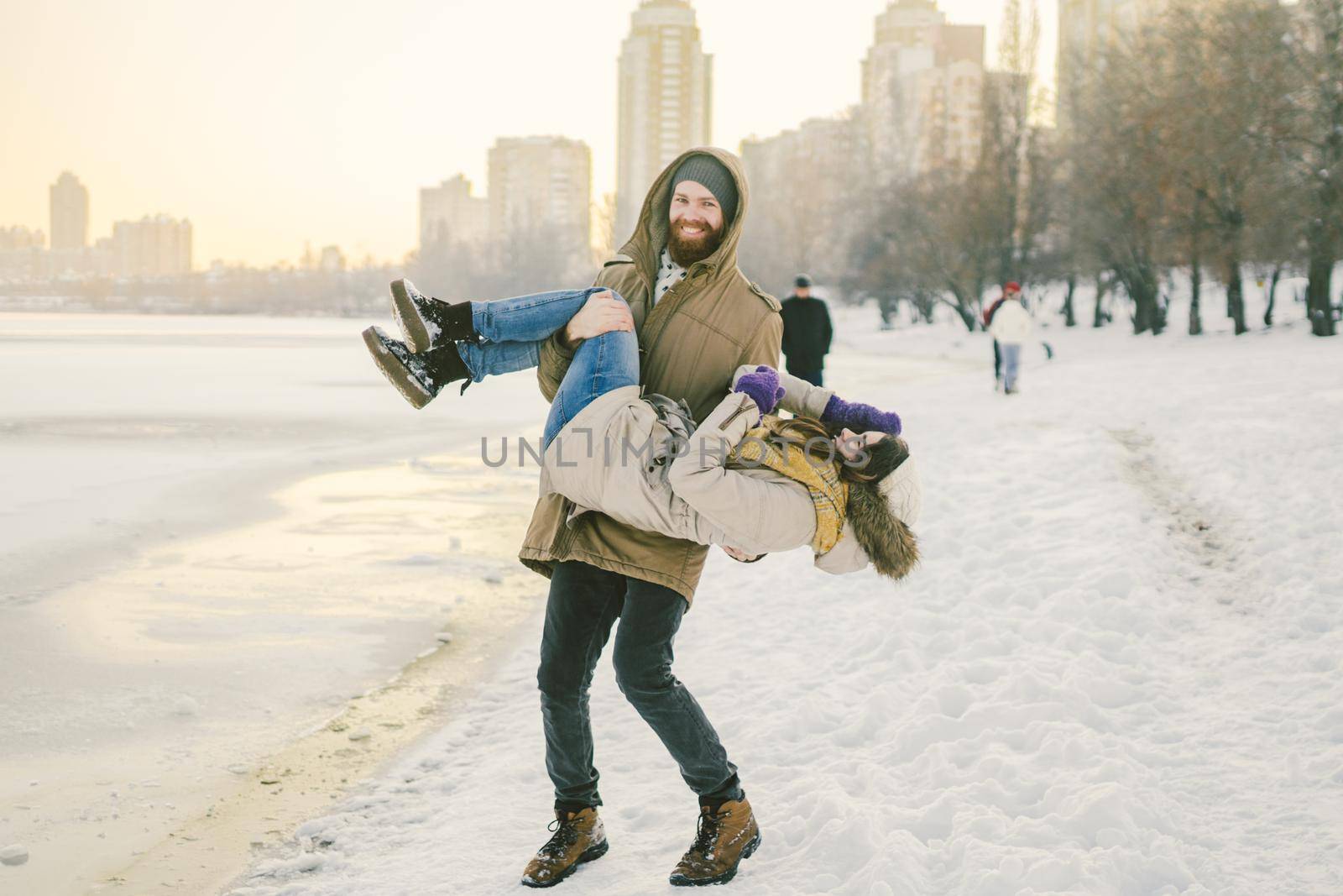 Theme outdoor activities in winter. Loving couple man and woman Caucasian joy happiness happiness love emotions on the shore of the lake. The guy wears holdings a girl. Valentine's day holiday