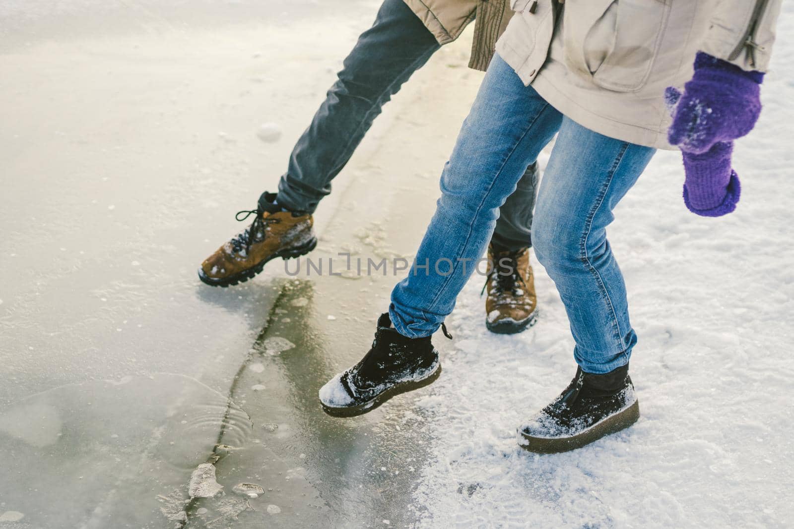 Trying the danger of the foot, testing the thin ice near the shore. A pair of lovers walk with a walk along a frozen lake to press foot on the ice by Tomashevska