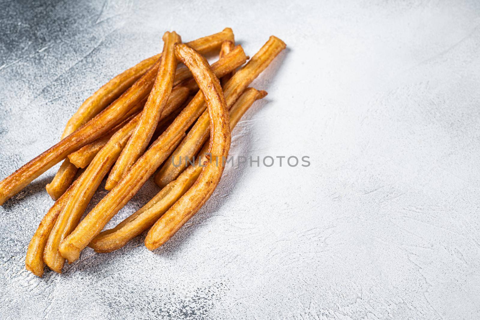 Churros fried sticks on kitchen table. White background. Top view. Copy space by Composter