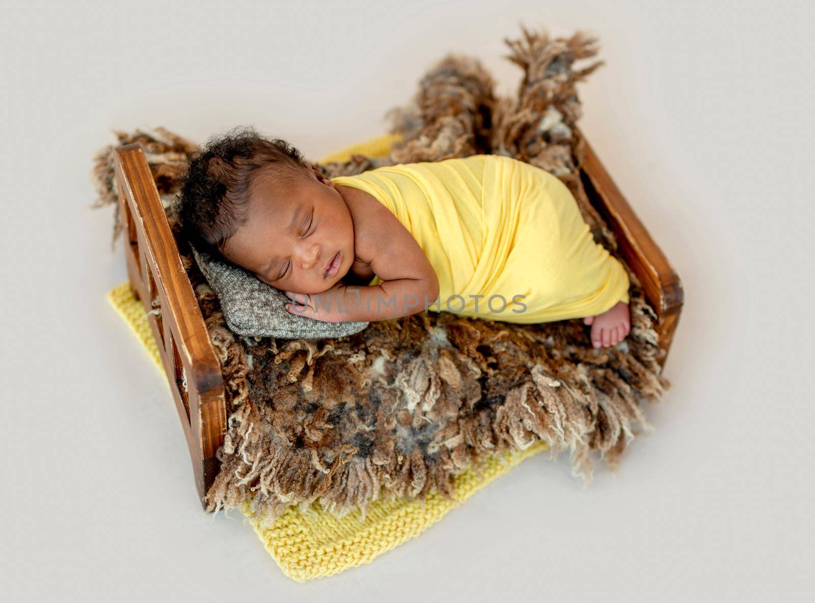 Adorable African newborn sleeping in wooden cradle