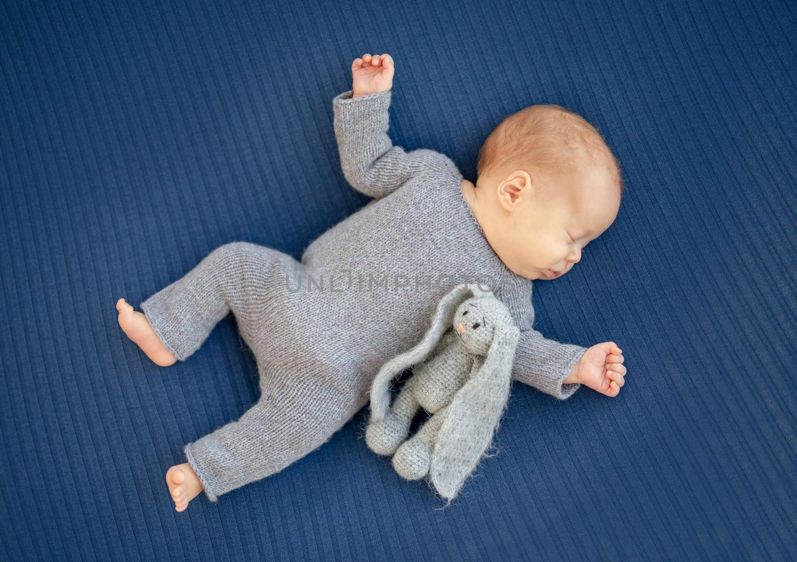 Charming newborn sleeping on back near toy