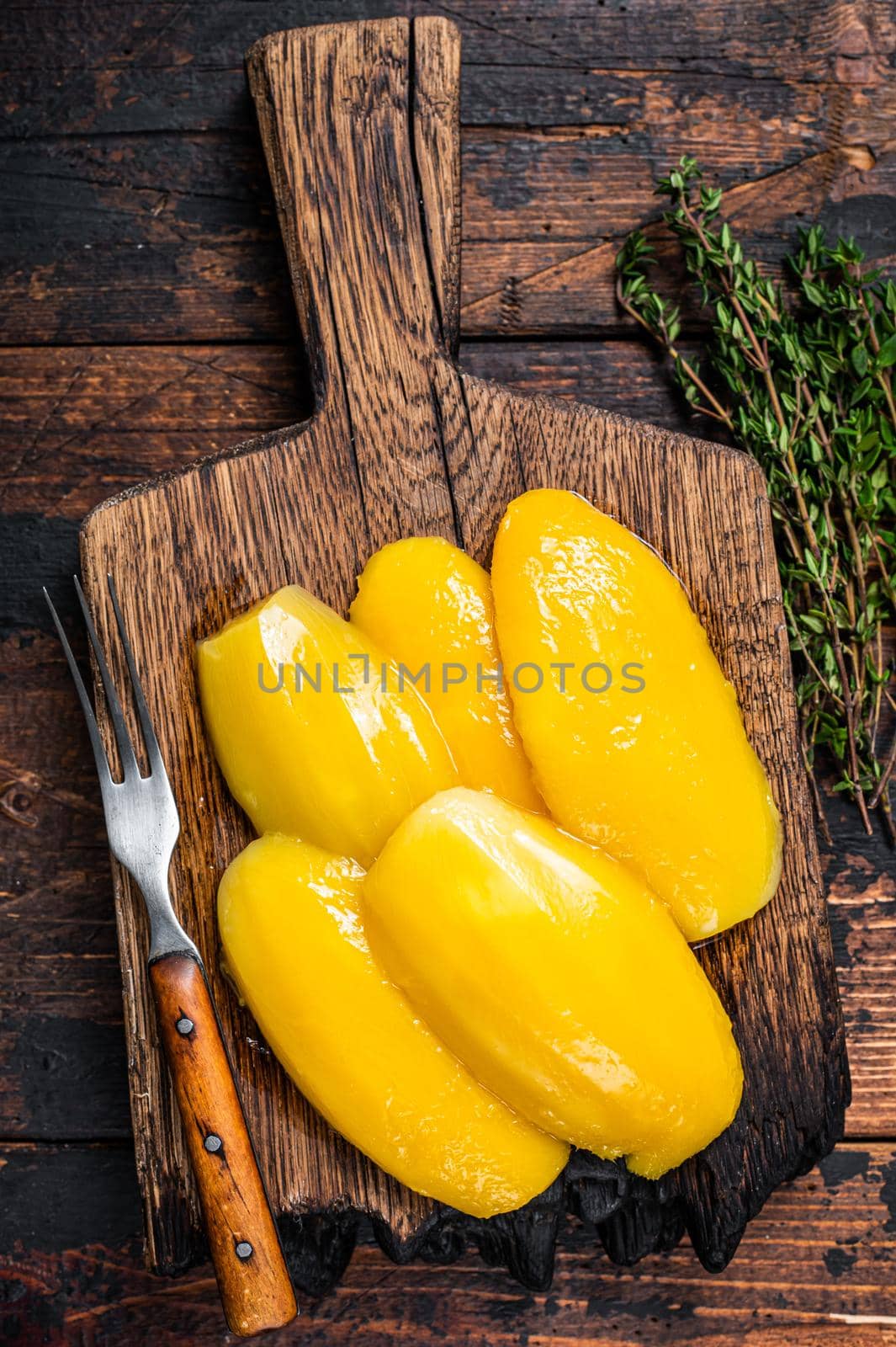 Preserve mango slices on a wooden board. Dark wooden background. Top view.