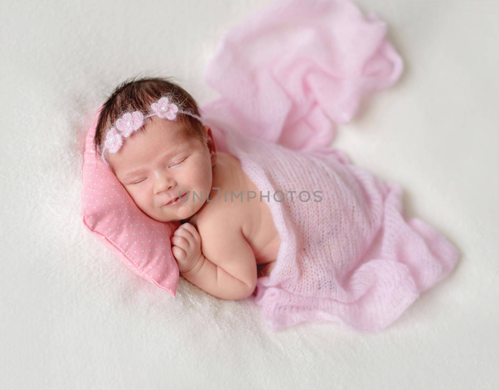 Cute sleeping newborn baby girl in a pink