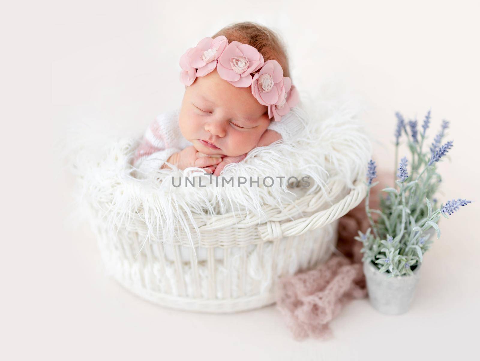 Sweet newborn baby girl resting in white basket