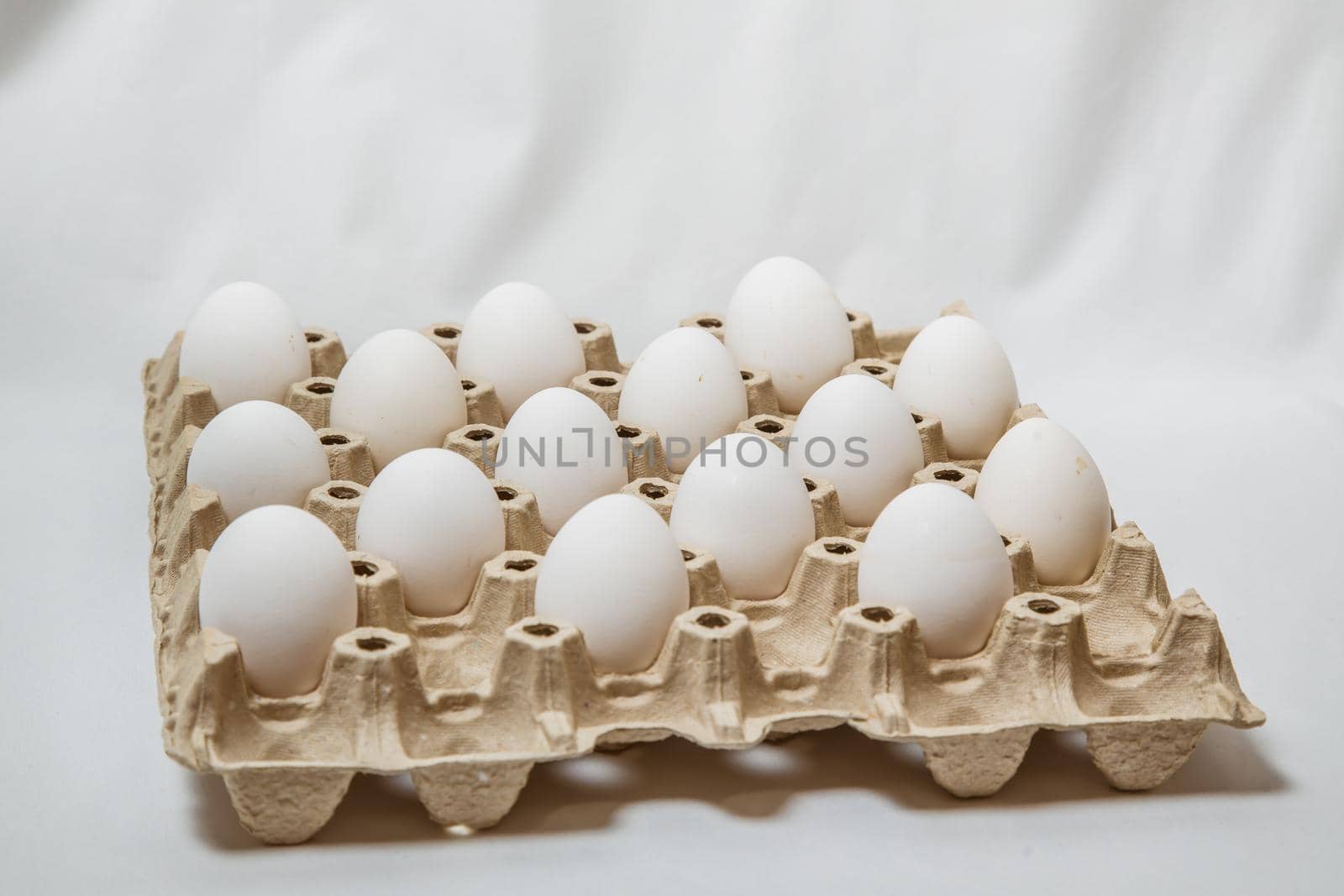 close up of carton box with distanced white eggs on white background. concept of quarantine rules