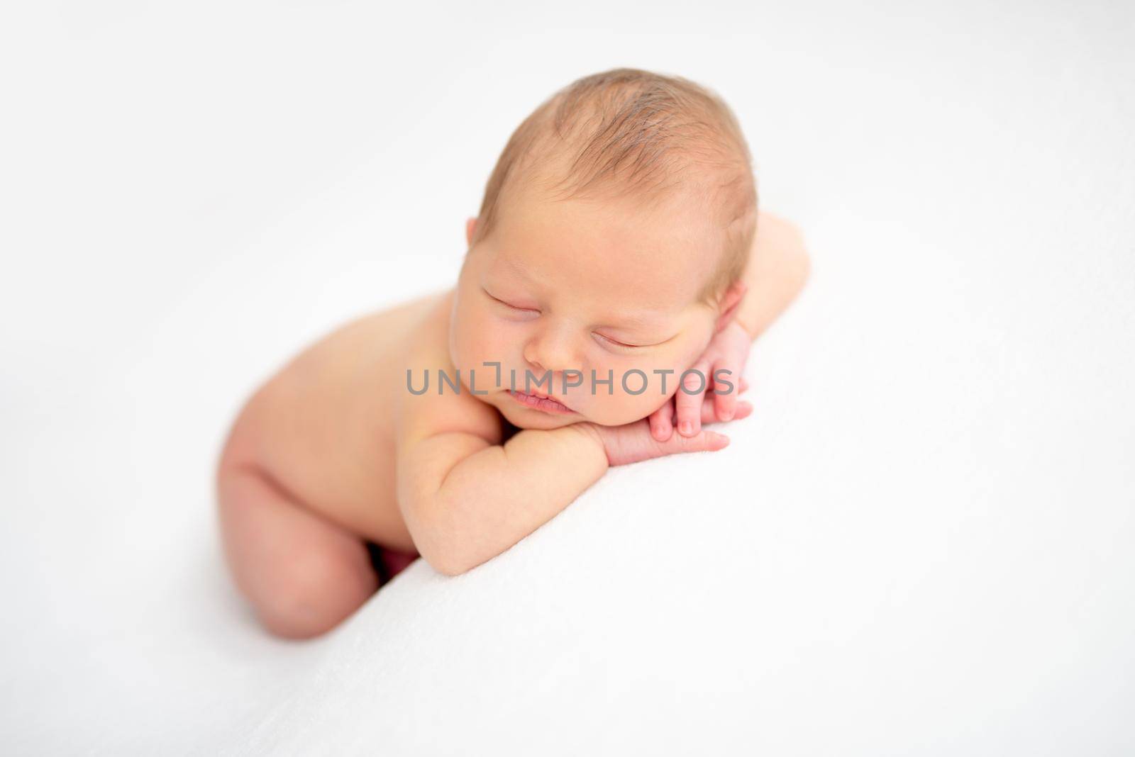 Charming naked baby sleeping on white blanket