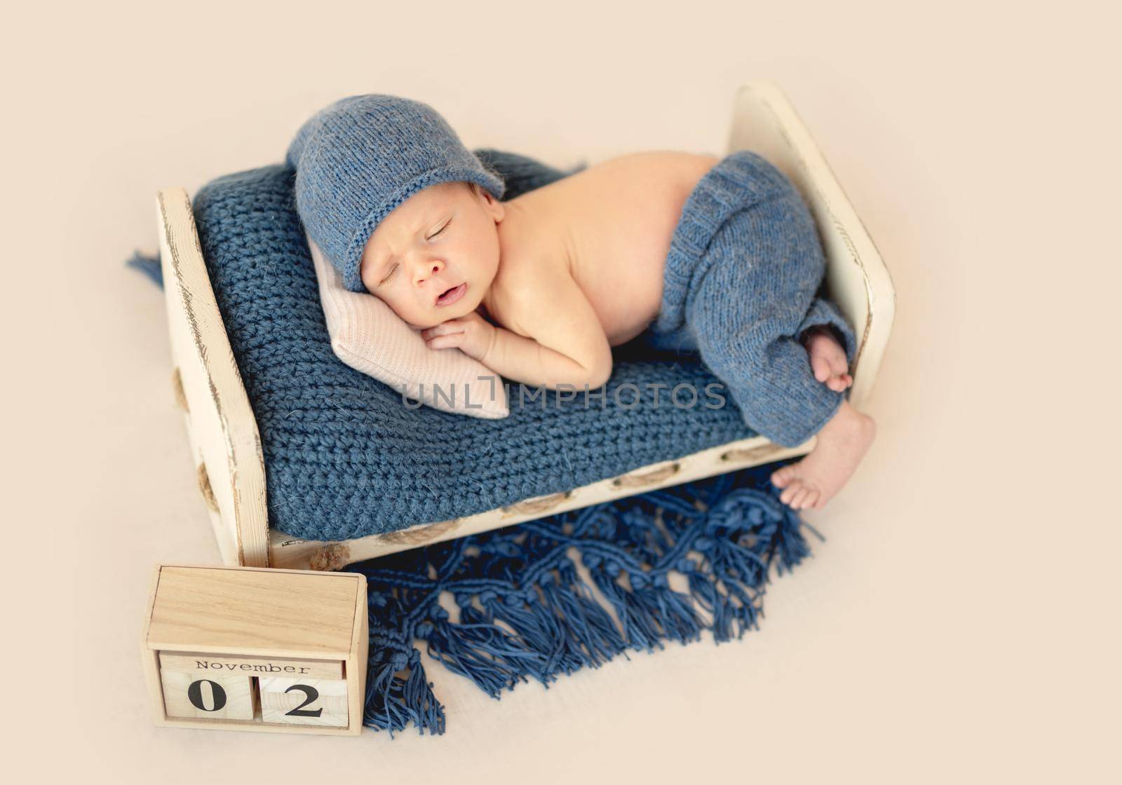 Charming newborn in cute hat sleeping on tiny pillow
