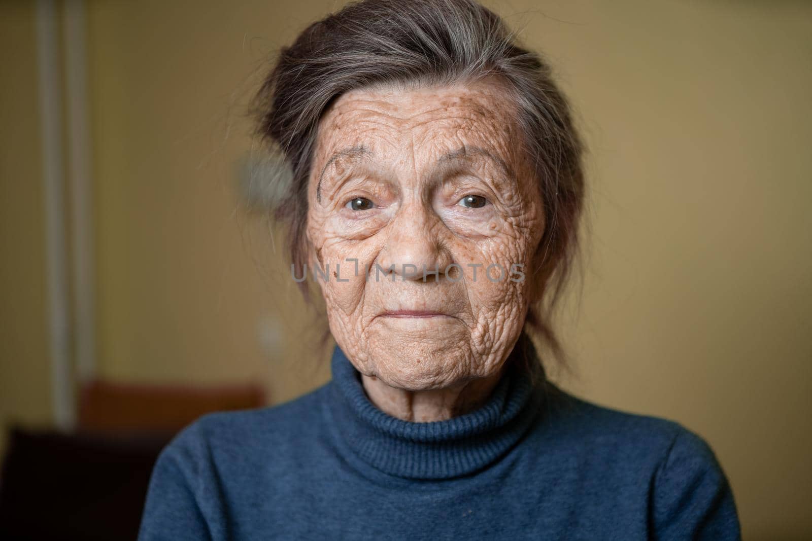 90 year old cute elderly woman with gray hair and wrinkles face, wearing sweater, portrait large, smiling and looking joyfully, background of room. Theme long-liver and aging, old people in good mood by Tomashevska