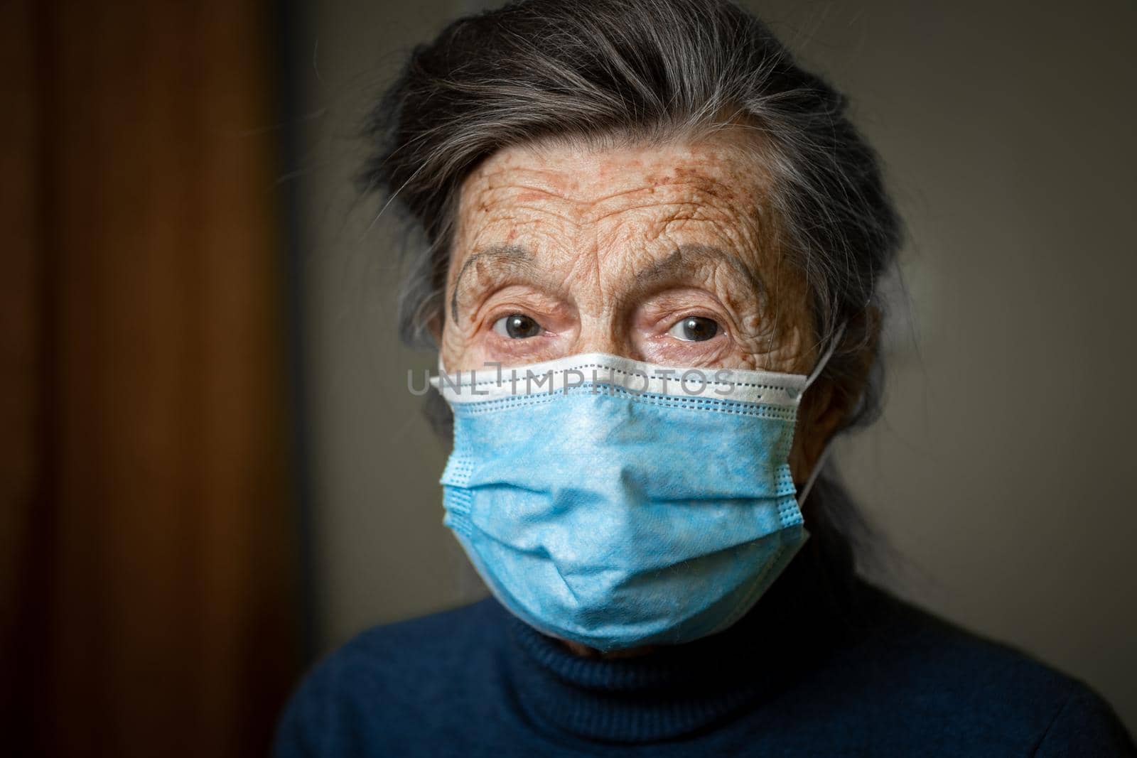 Wise look of old woman with medical mask on face encourages you to keep your distance and use protective equipment, health safety during an covid 19. Portrait of senior looking at camera, elderly care
