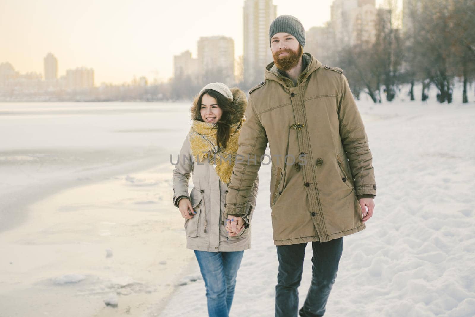 Theme Christmas holidays winter new year. Young stylish Caucasian loving couple Heteresexual walking on the shore of a frozen lake. Date. Valentines Day in winter at sunset. Love and Romance Theme by Tomashevska