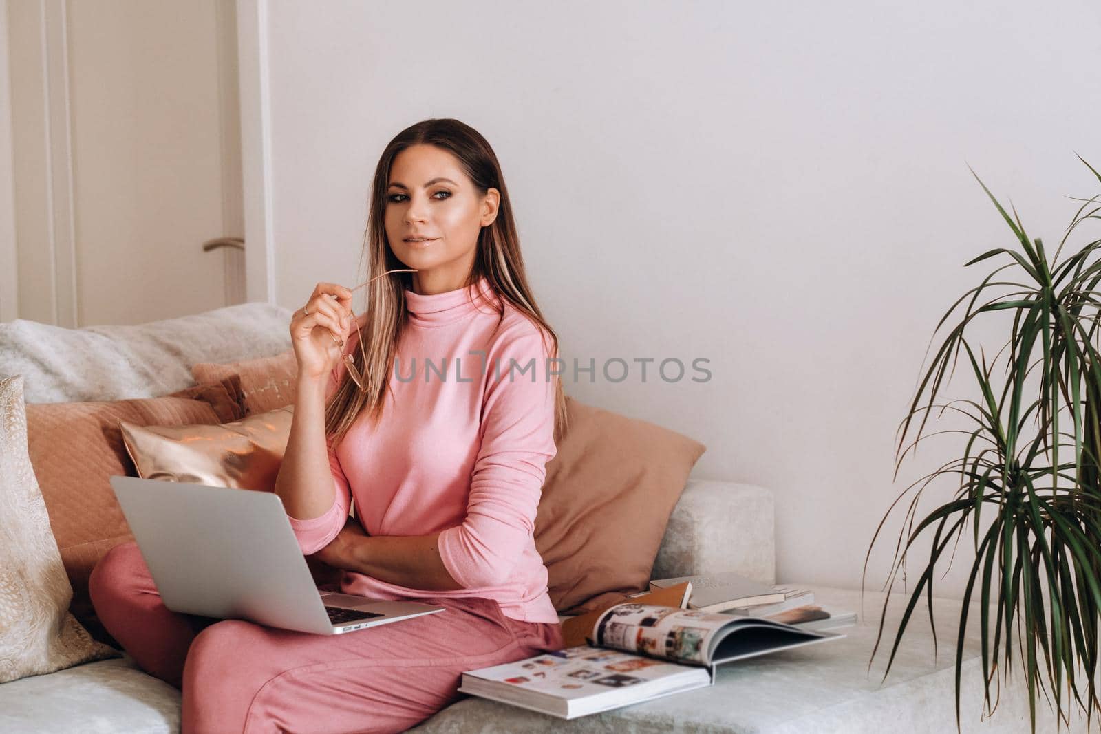 a girl in the morning in pajamas and glasses at home works on a laptop, a girl self-isolates at home and rests on the couch and watches a laptop.Household chores by Lobachad