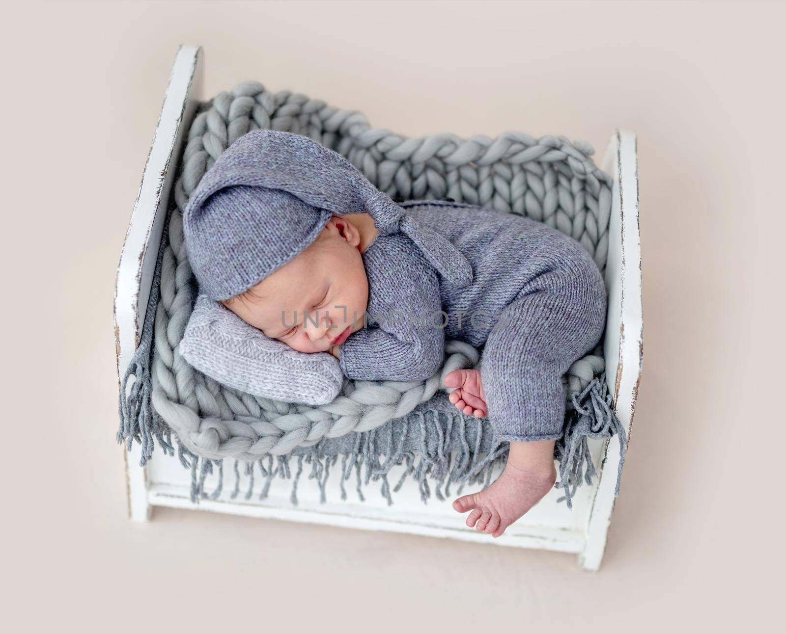 Cute newborn sleeping on tiny bed